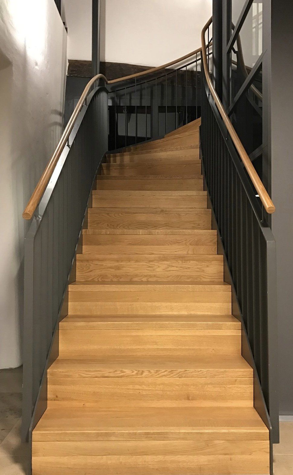 Eine Holztreppe mit einem Metallgeländer in einem Gebäude.