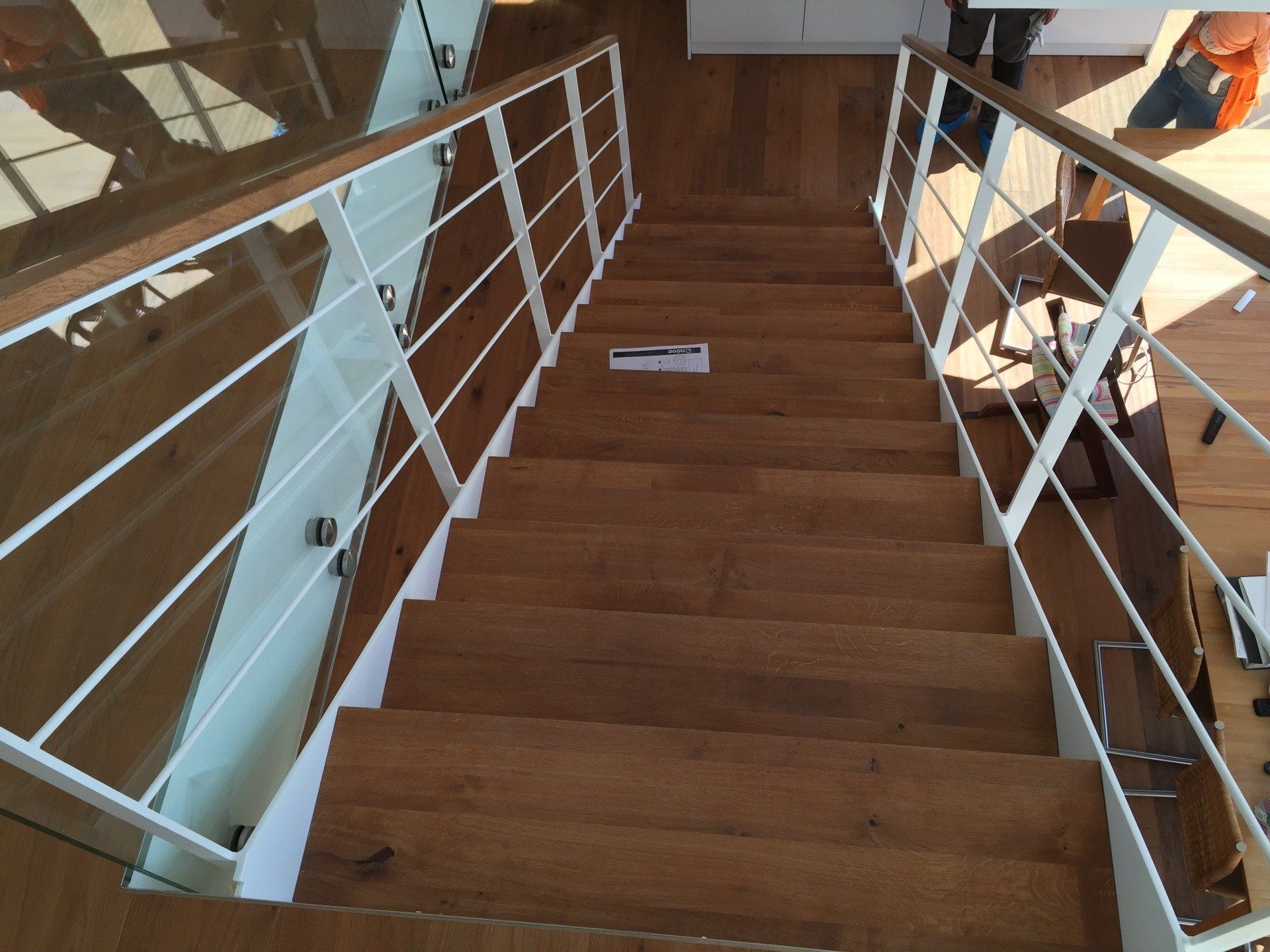 Eine Holztreppe mit weißem Geländer und Glasgeländer