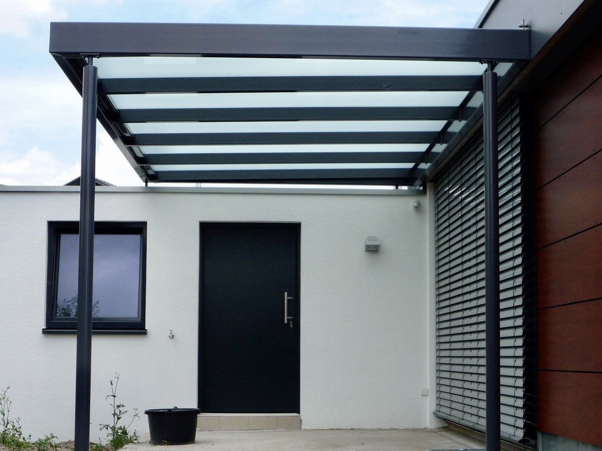 Ein weißes Haus mit einer schwarzen Tür und einem Glasdach