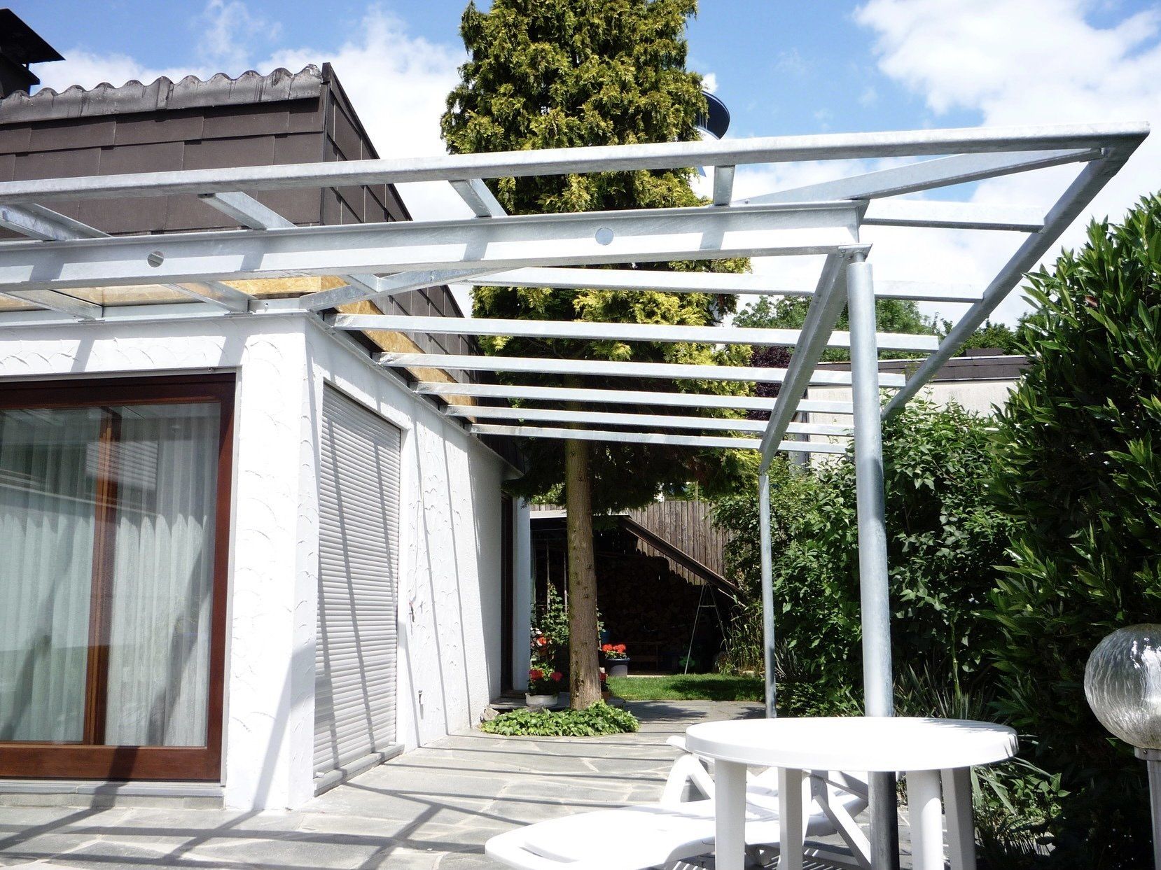 Ein weißes Haus mit einer Pergola und einem Tisch davor