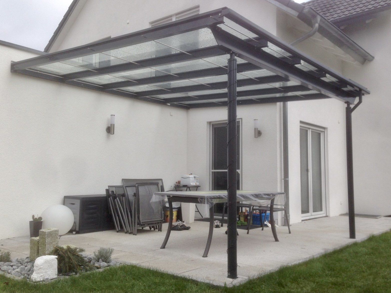 Eine Terrasse mit Tisch und Stühlen unter einem Glasdach.