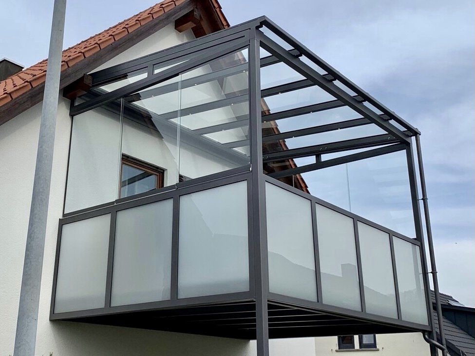 An der Seite eines Hauses befindet sich ein Balkon mit Glasdach.