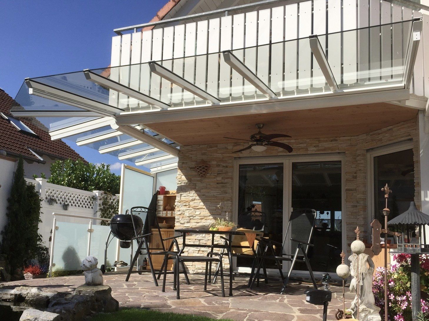 Eine Terrasse mit Tisch und Stühlen unter einem Baldachin mit Deckenventilator.