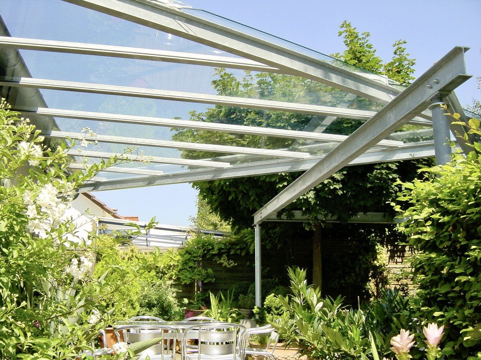 Ein Garten mit Tischen und Stühlen unter einem Glasdach