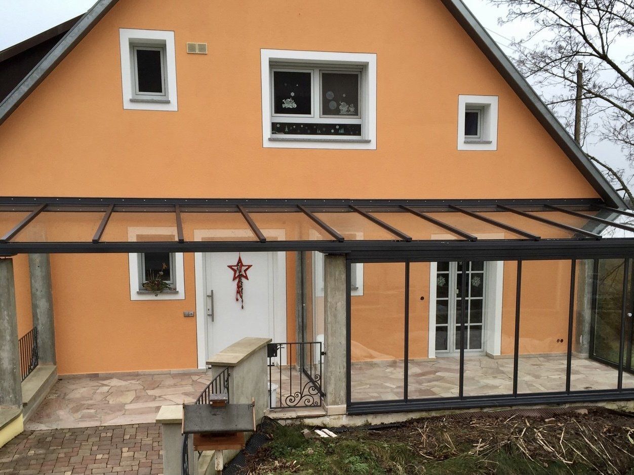 Ein orangefarbenes Haus mit einer glasüberdachten Veranda und einer weißen Tür
