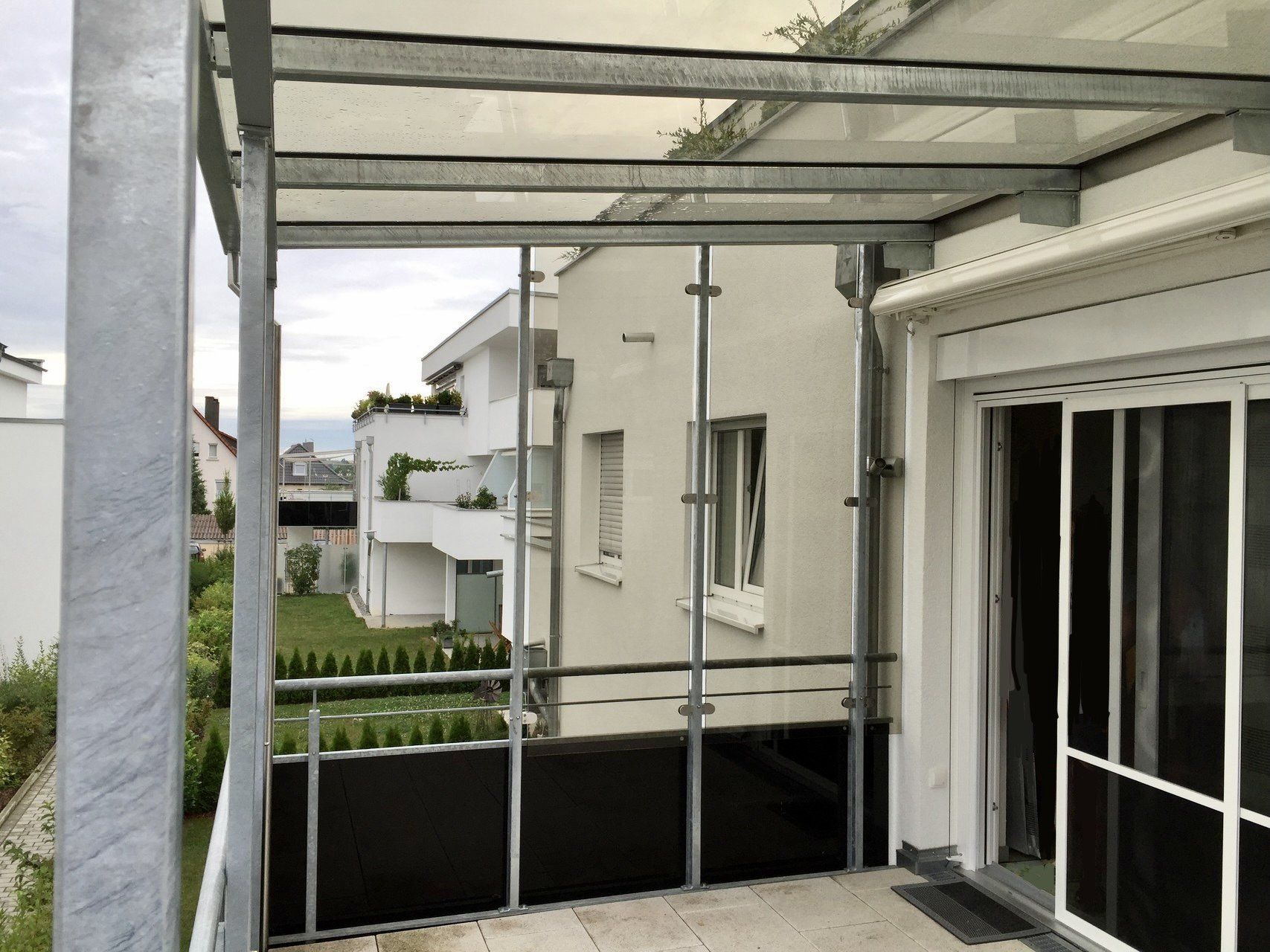 Ein Balkon mit Glasdach und Glasschiebetüren