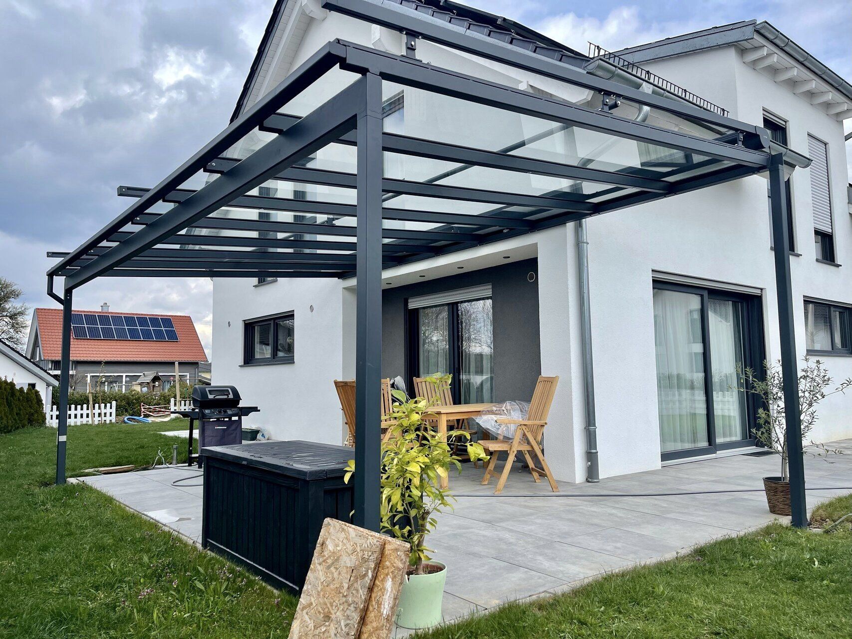 Ein weißes Haus mit einer Glaspergola davor.