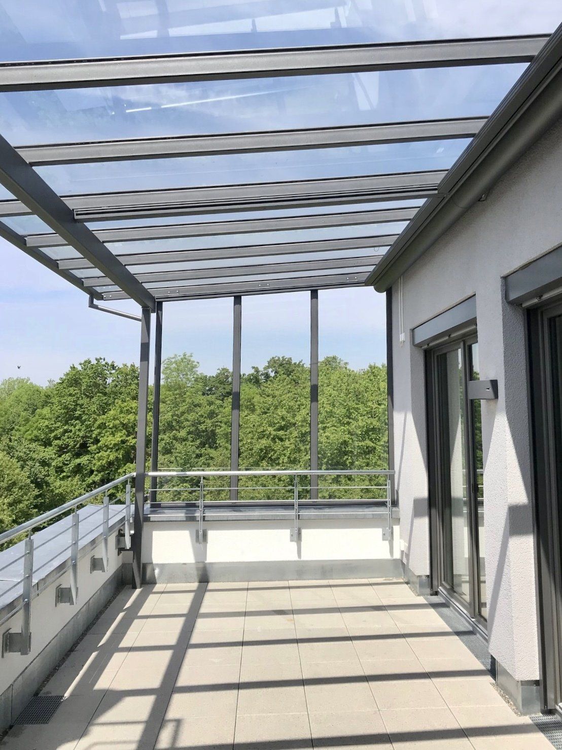 Ein Balkon mit Glasdach und Bäumen im Hintergrund