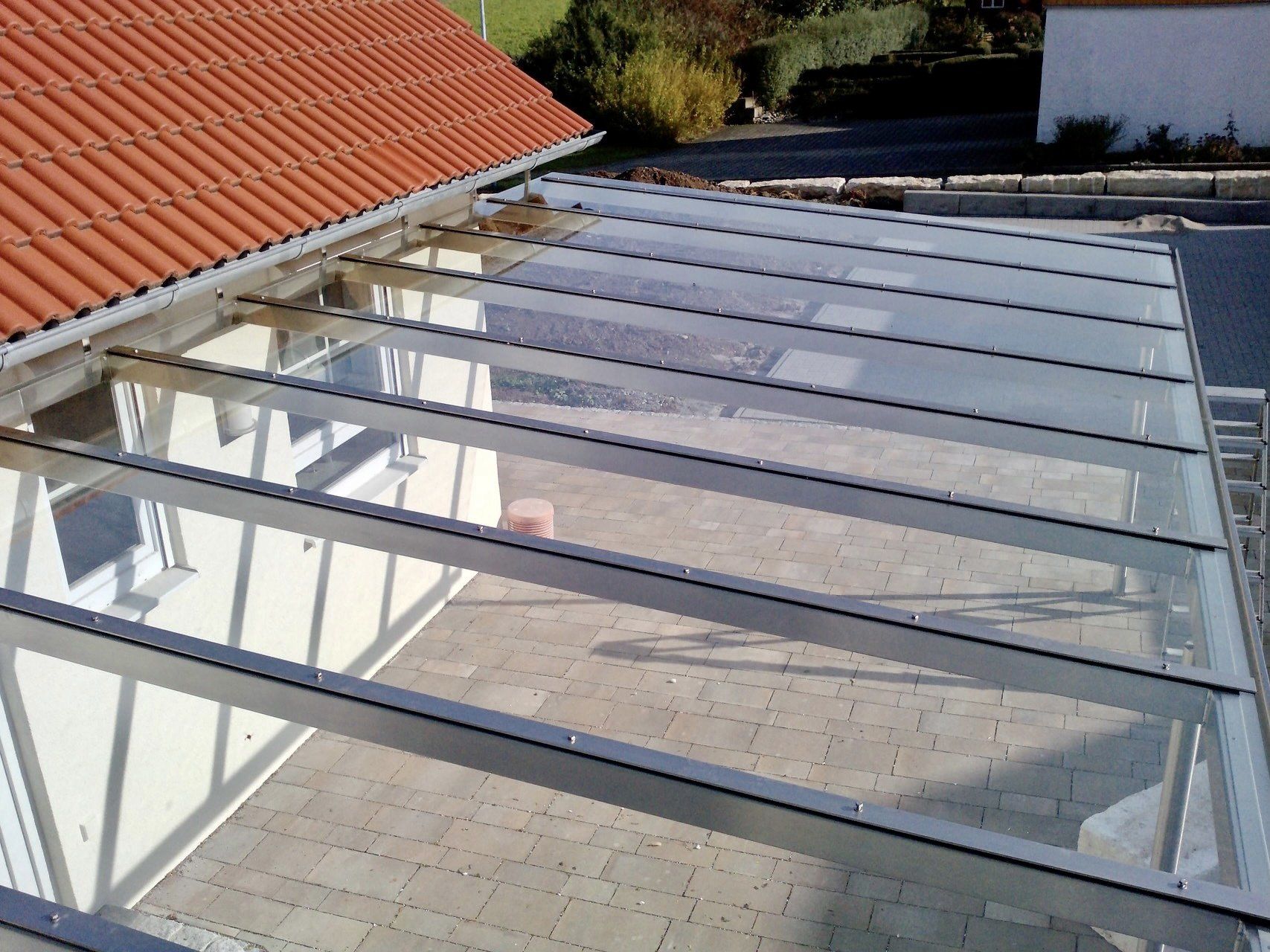 Ein klares Glasdach mit einem roten Dach im Hintergrund