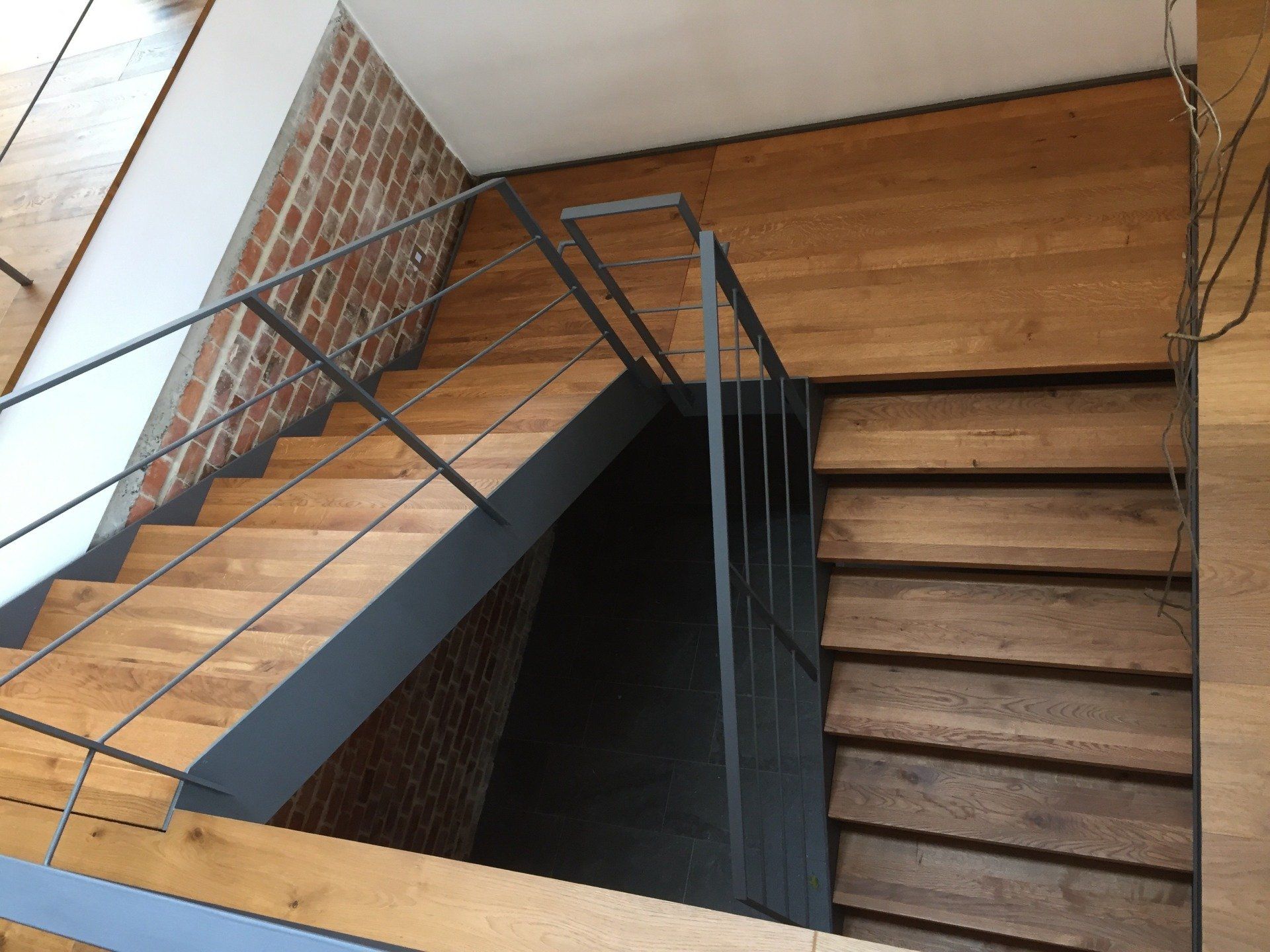 Eine Holztreppe mit einem Metallgeländer und einer Ziegelwand
