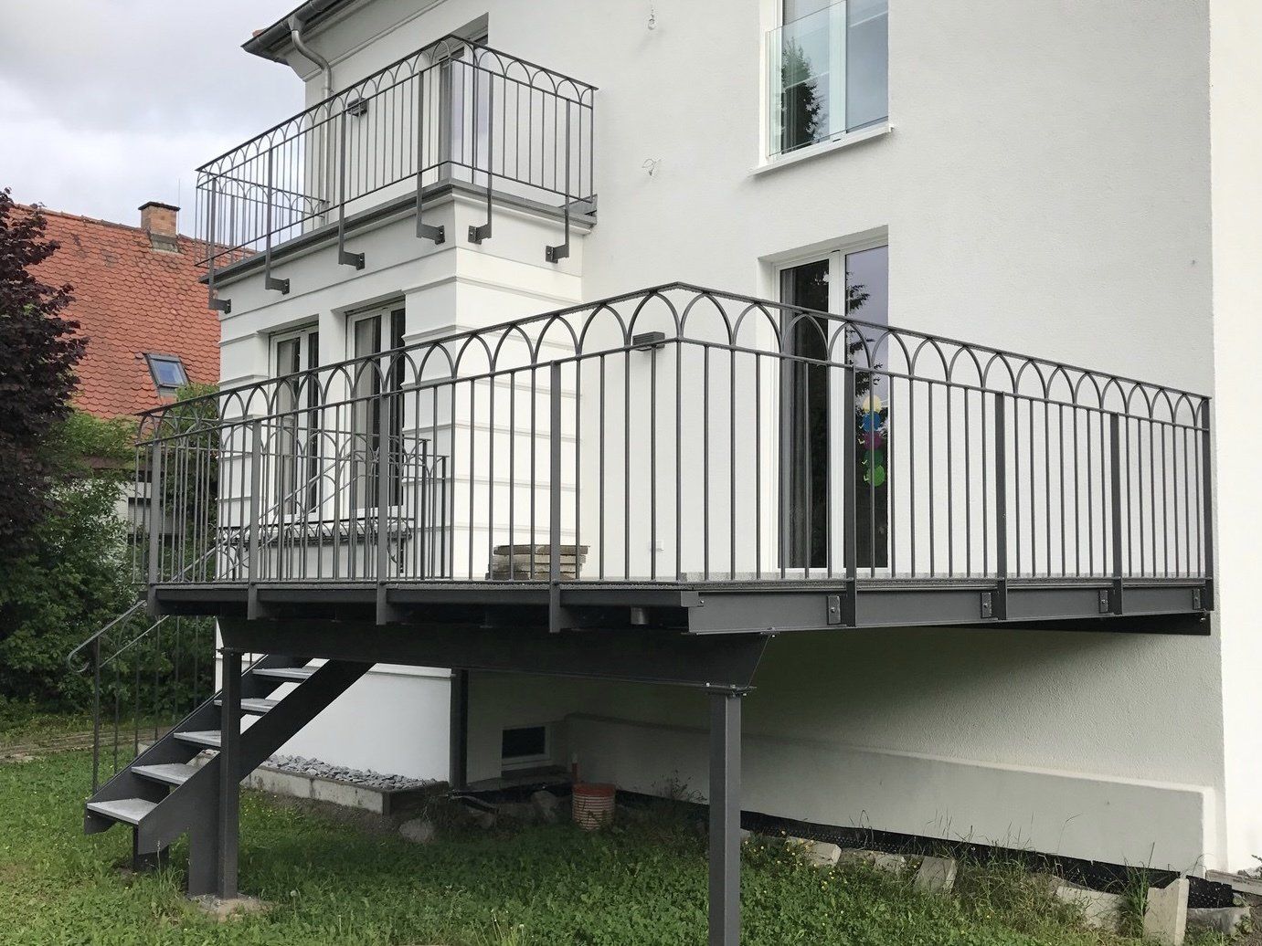 Ein weißes Haus mit einem Balkon und einer Treppe an der Seite.