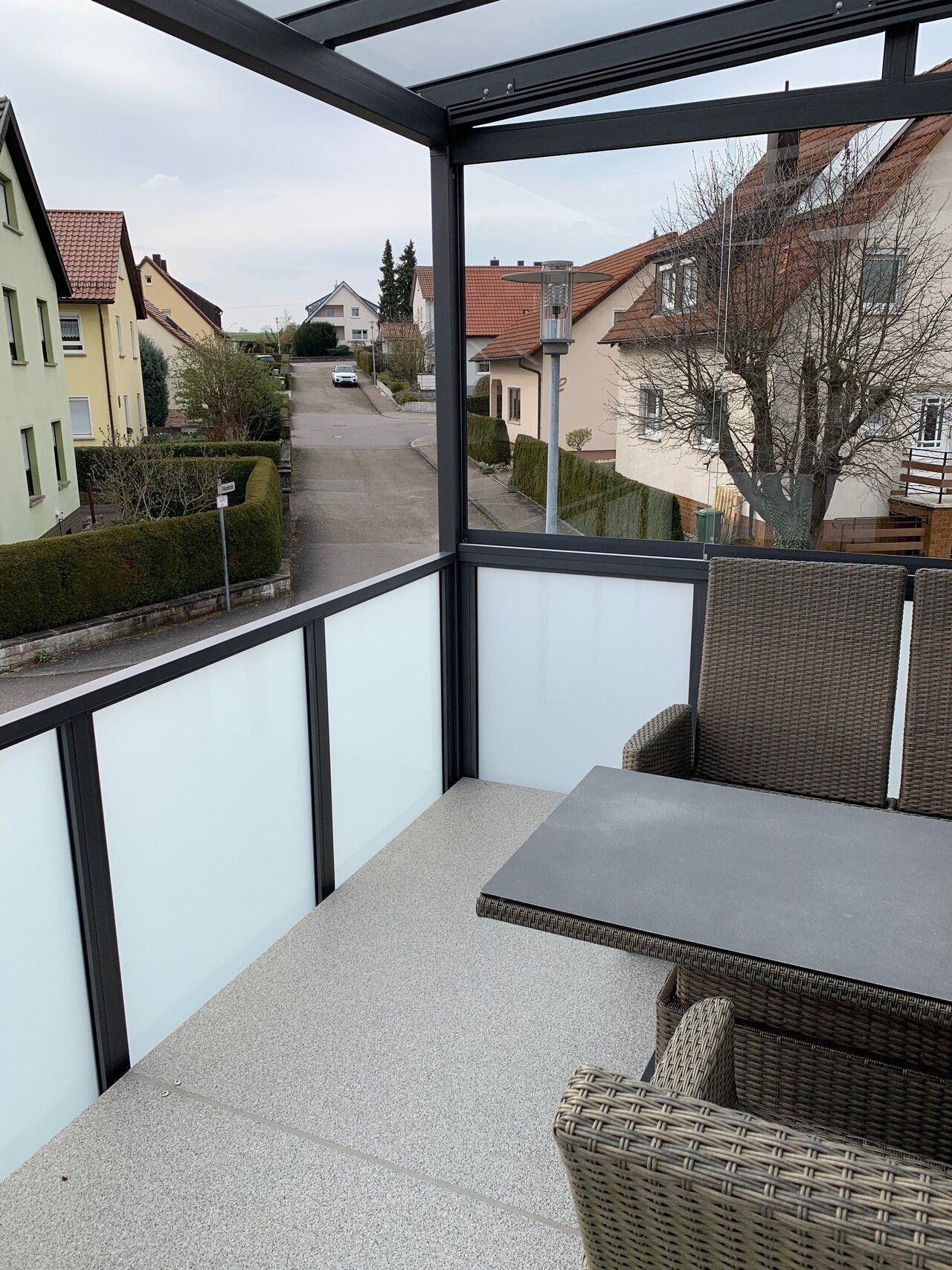Ein Balkon mit Tisch und Stühlen mit Blick auf eine Straße
