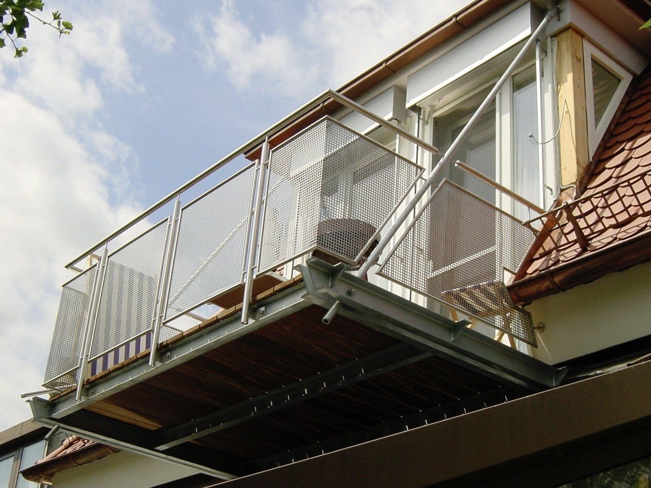 Ein Balkon an der Seite eines Gebäudes mit einem Geländer aus Edelstahl