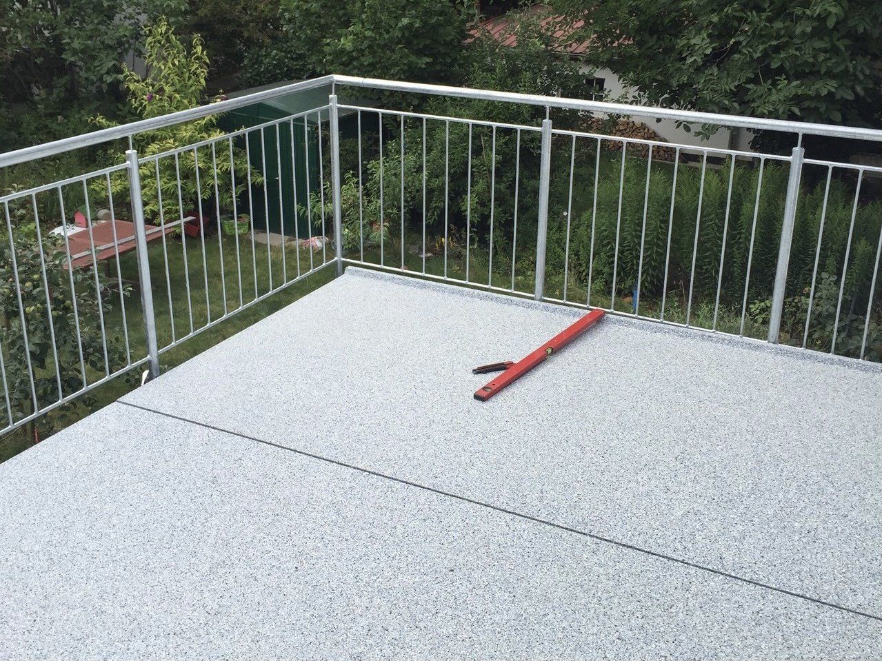 Ein Balkon mit einem Metallgeländer und einer roten Ebene darauf.