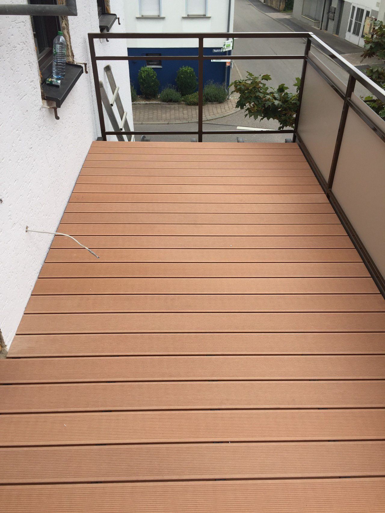 Ein Balkon mit Holzdeck und Metallgeländer.