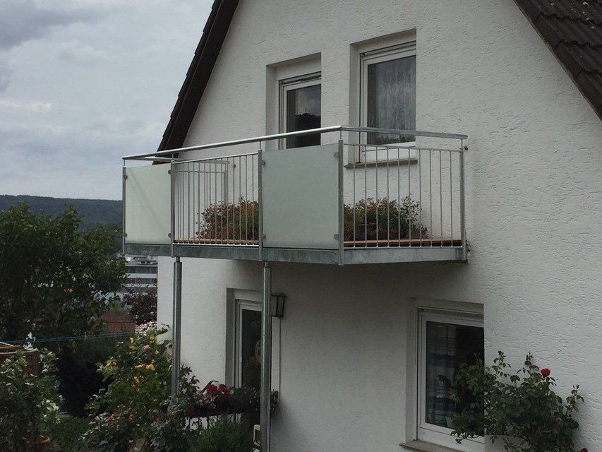 Ein weißes Haus mit einem Balkon an der Seite