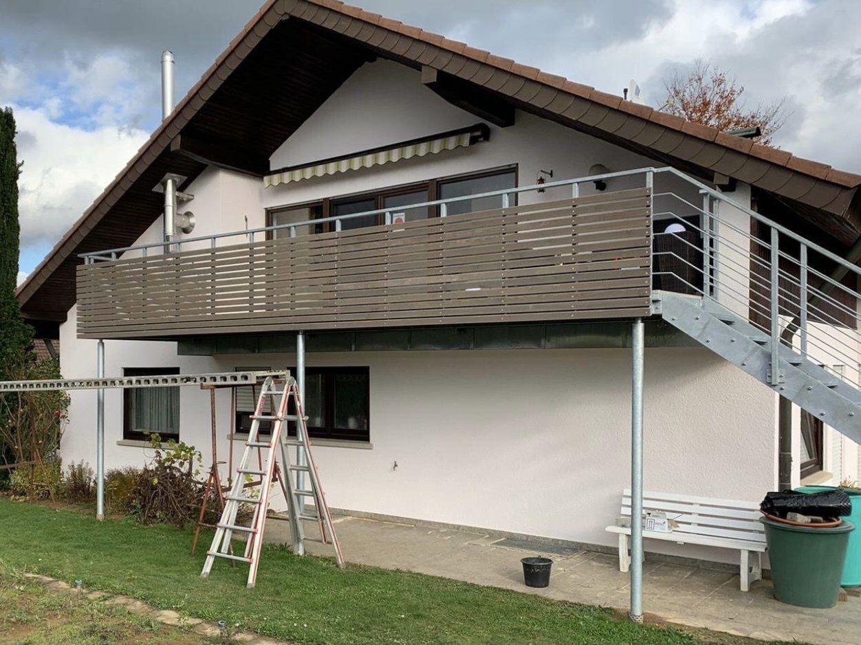 Ein weißes Haus mit einem Balkon und einer Treppe an der Seite.