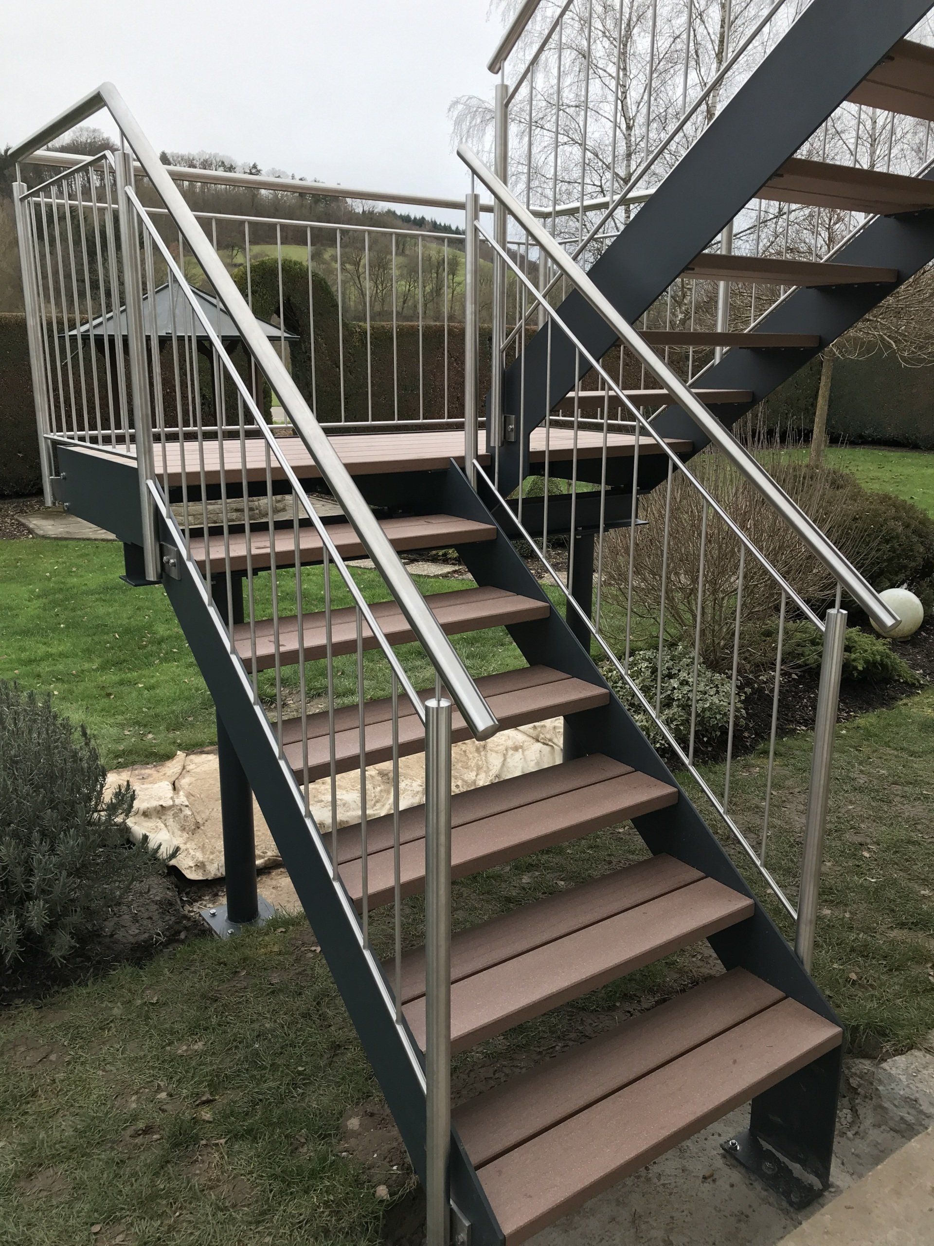 Eine Treppe mit Holzstufen und einem Geländer aus Edelstahl