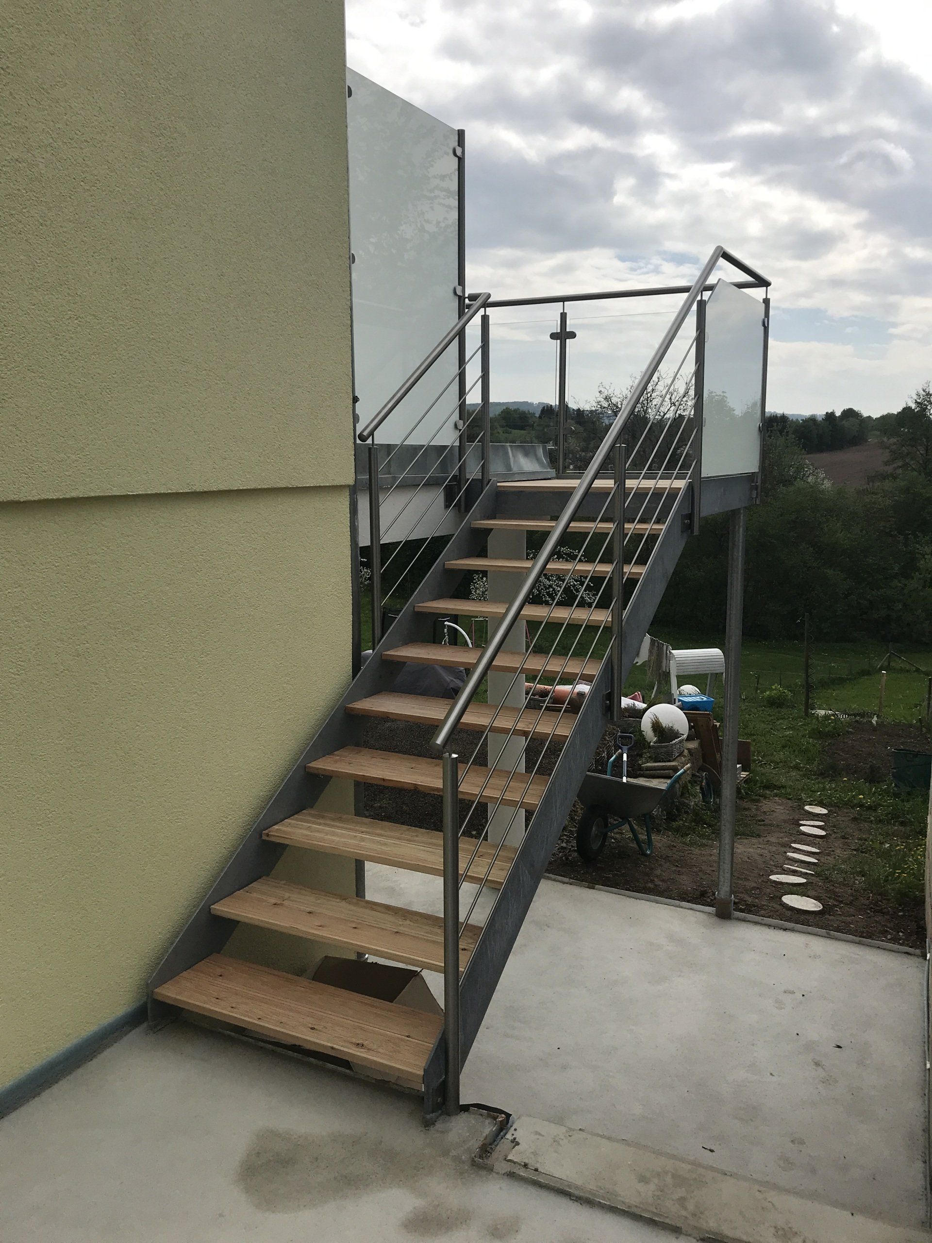 Eine Treppe mit Holzstufen und einem Glasgeländer an der Seite eines Gebäudes.