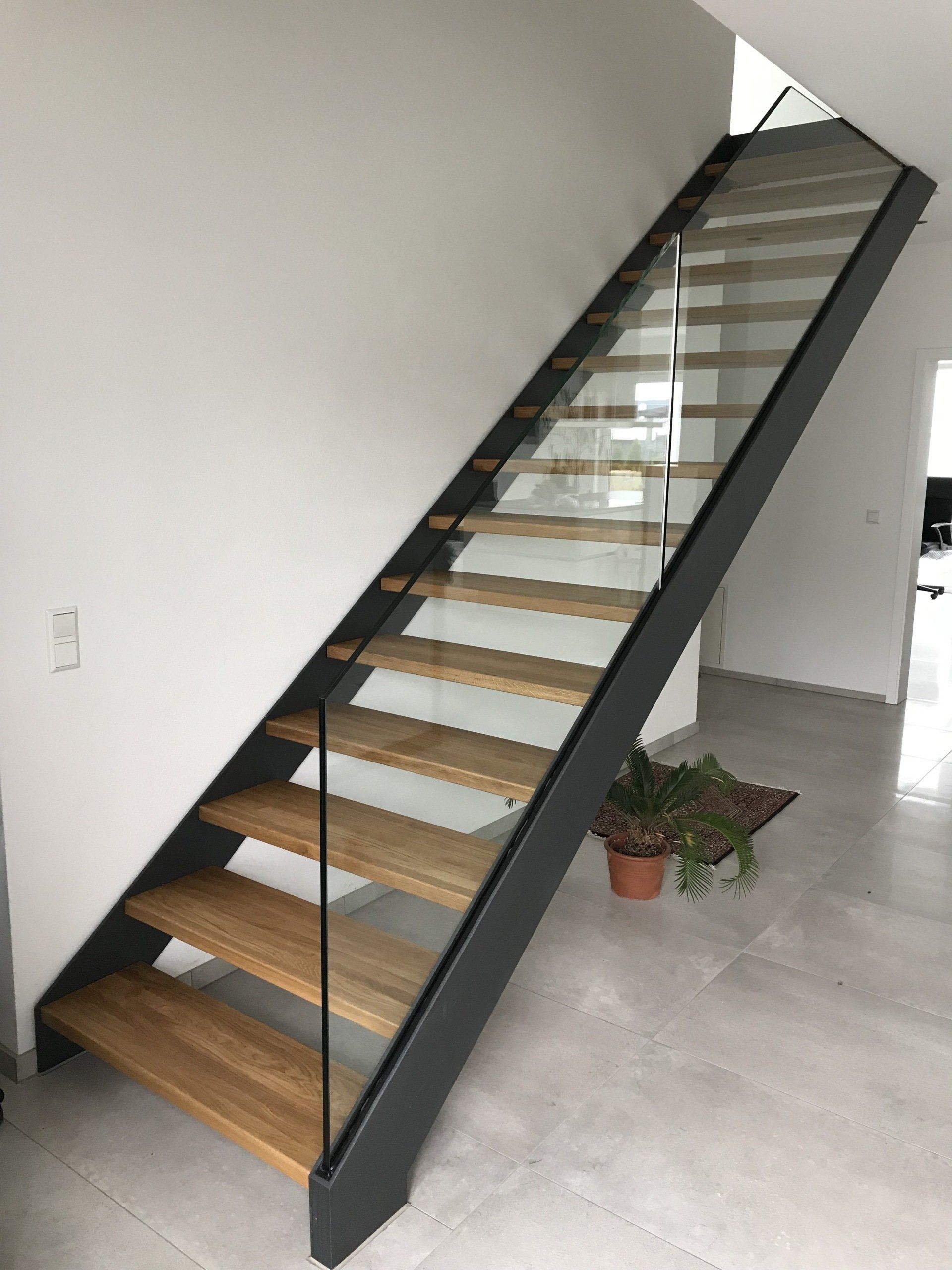 Eine Treppe mit Holzstufen und einem Glasgeländer in einem Raum.