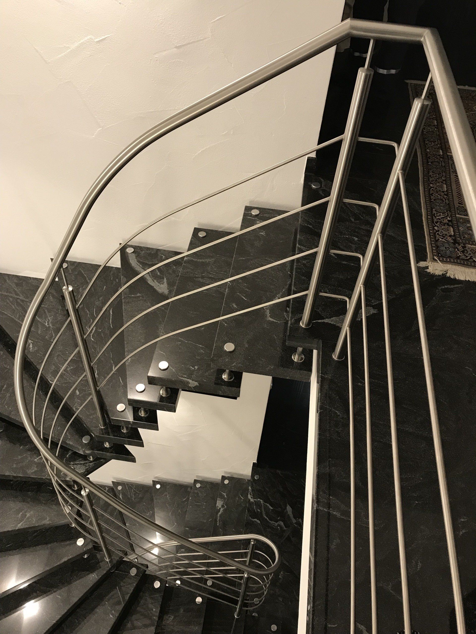 Ein Schwarzweißfoto einer Wendeltreppe mit einem Geländer aus Edelstahl
