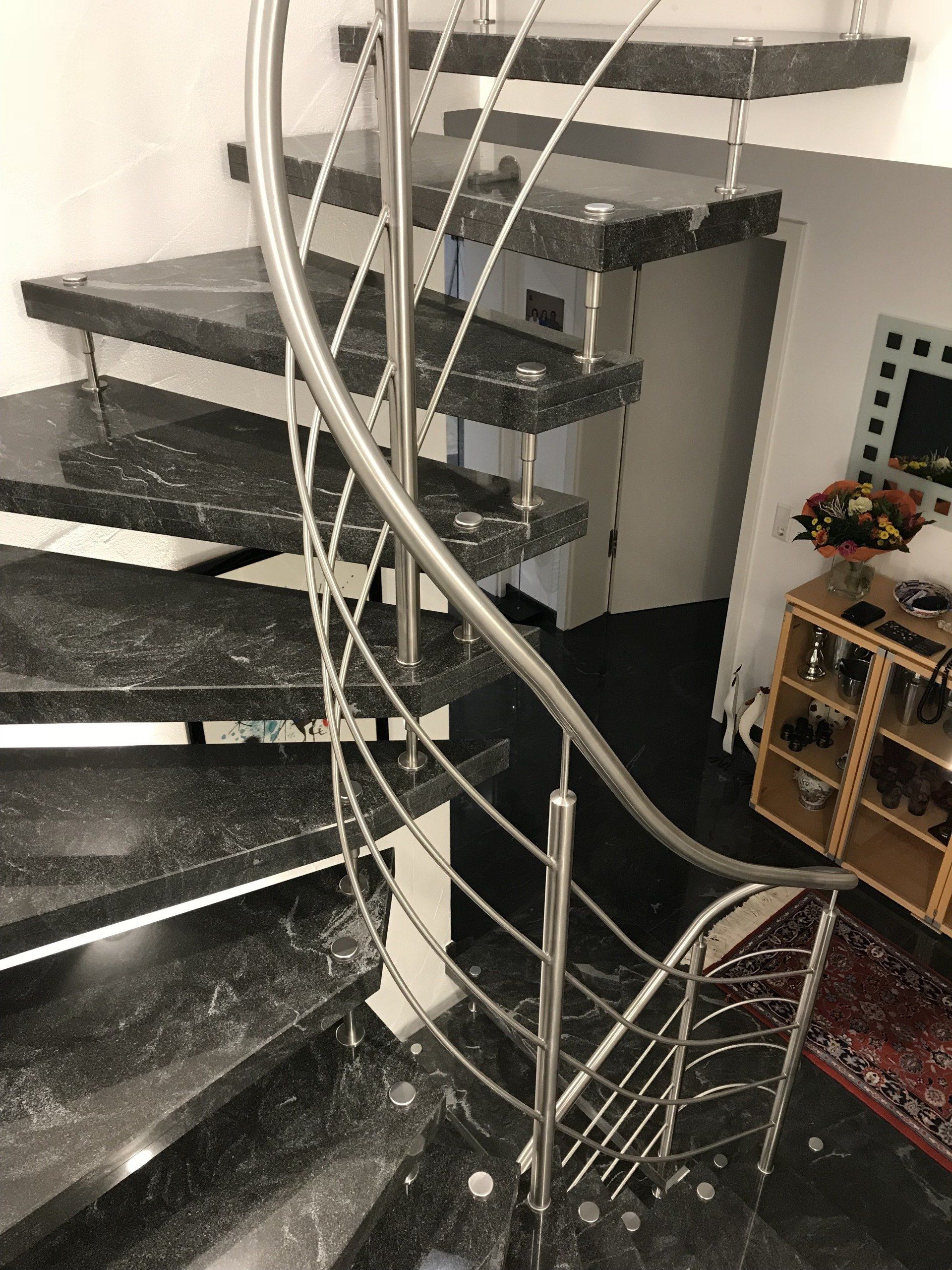 Eine Wendeltreppe mit Edelstahlgeländer in einem Wohnzimmer.