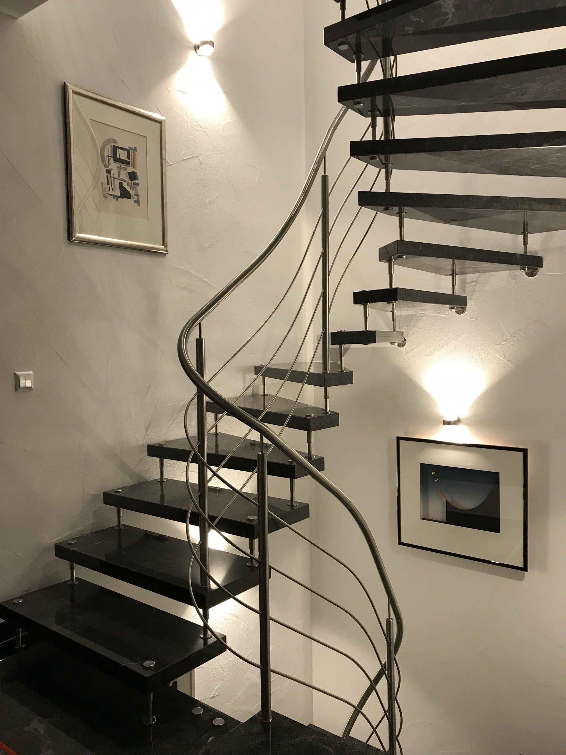 Ein Schwarzweißfoto einer Wendeltreppe mit einem Geländer aus Edelstahl.