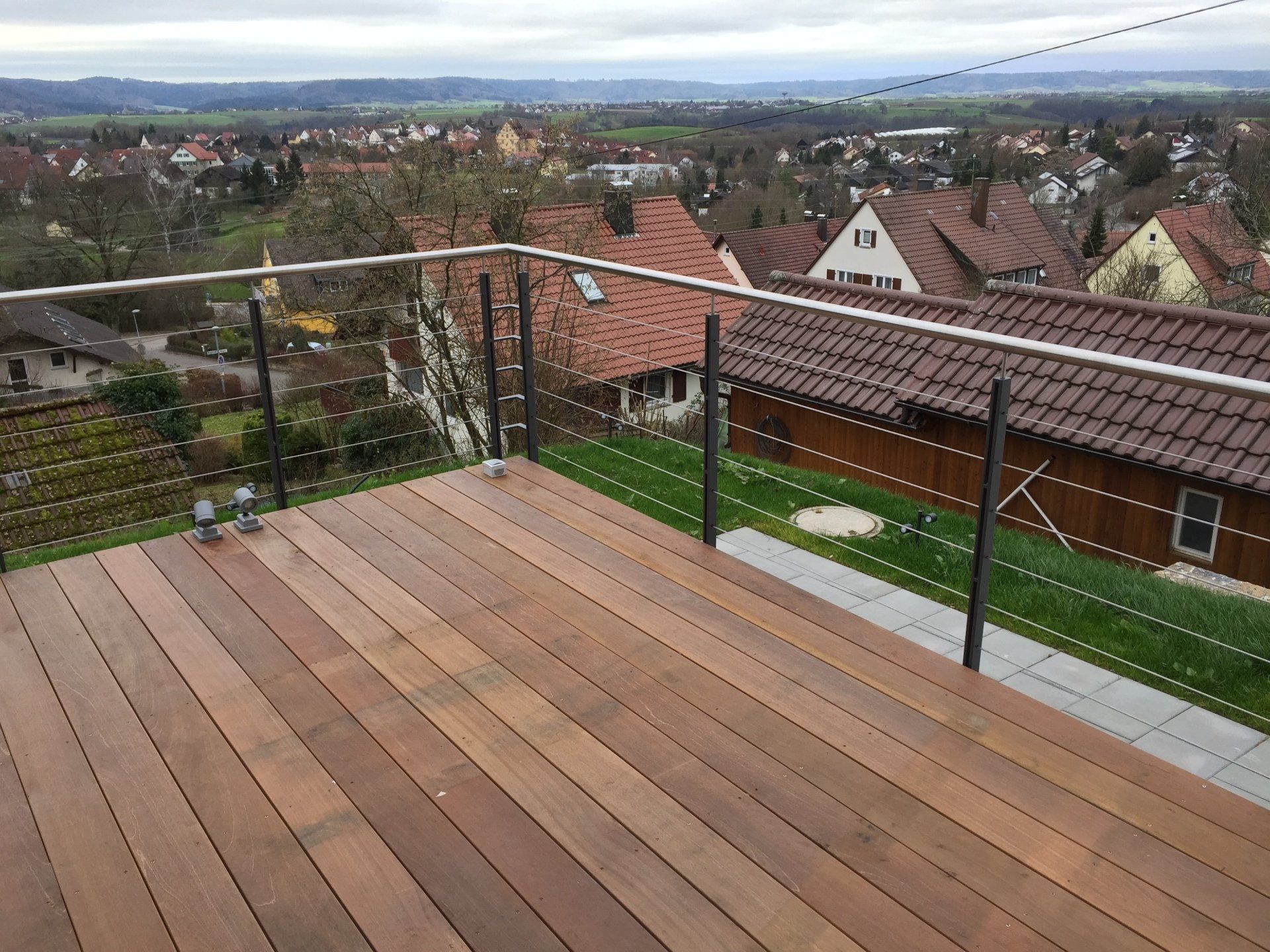 Ein Holzdeck mit Edelstahlgeländer und Blick auf die Stadt.
