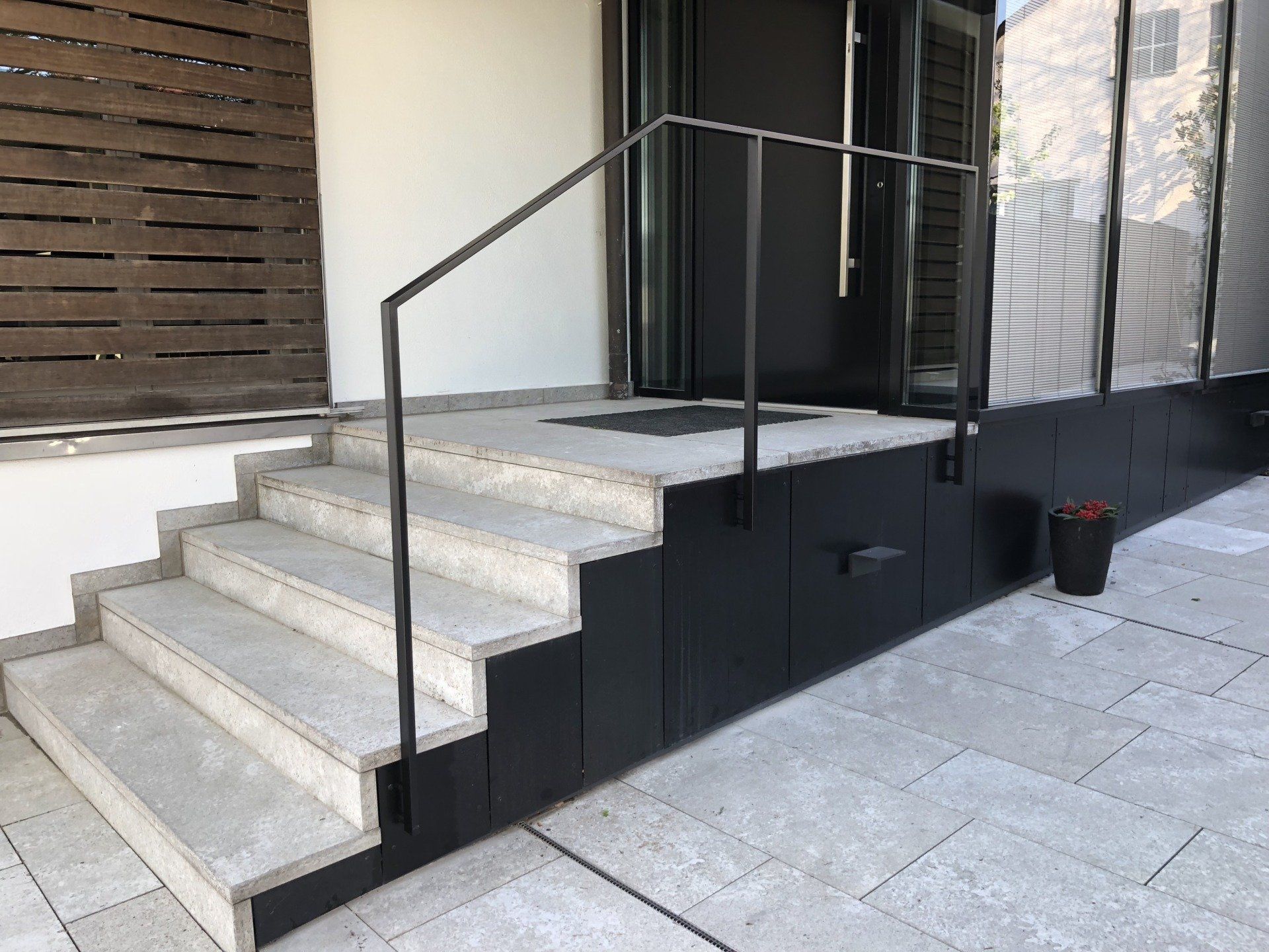 Eine Treppe, die zu einer Tür mit einem schwarzen Geländer führt