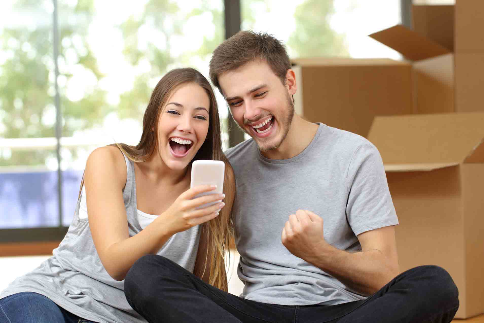 Euphoric couple moving house and watching phone