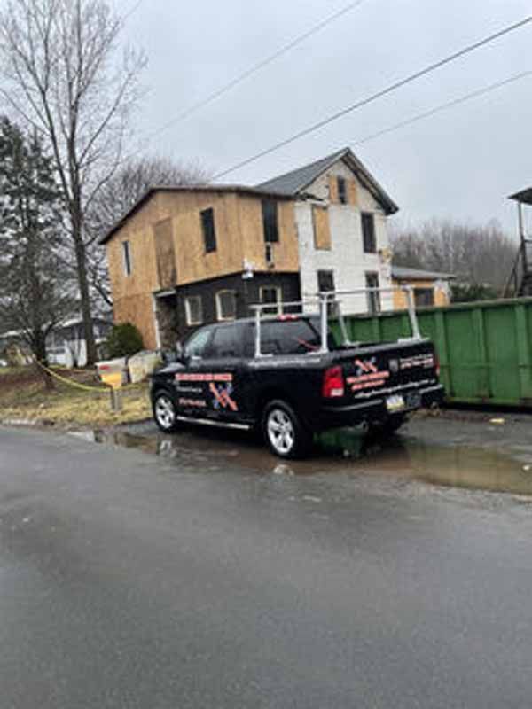 Black truck parked in front of a house under construction; cloudy, exterior shot.