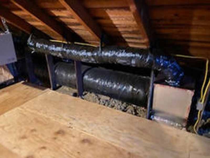 Air ducts in attic space, with wood beams and flooring.