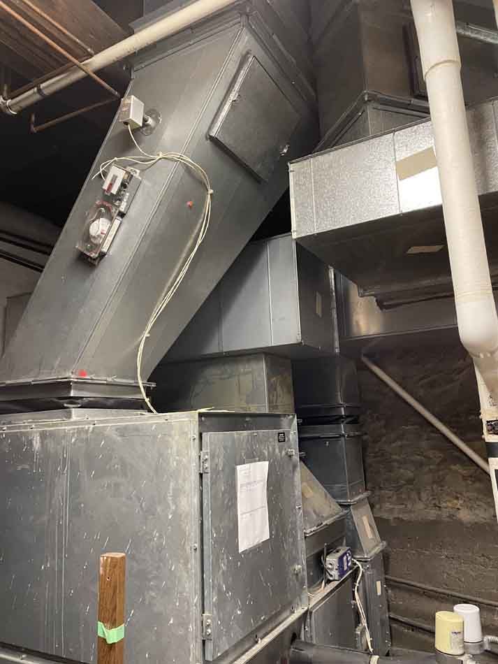 Large industrial HVAC system with ducts and controls in a basement setting.