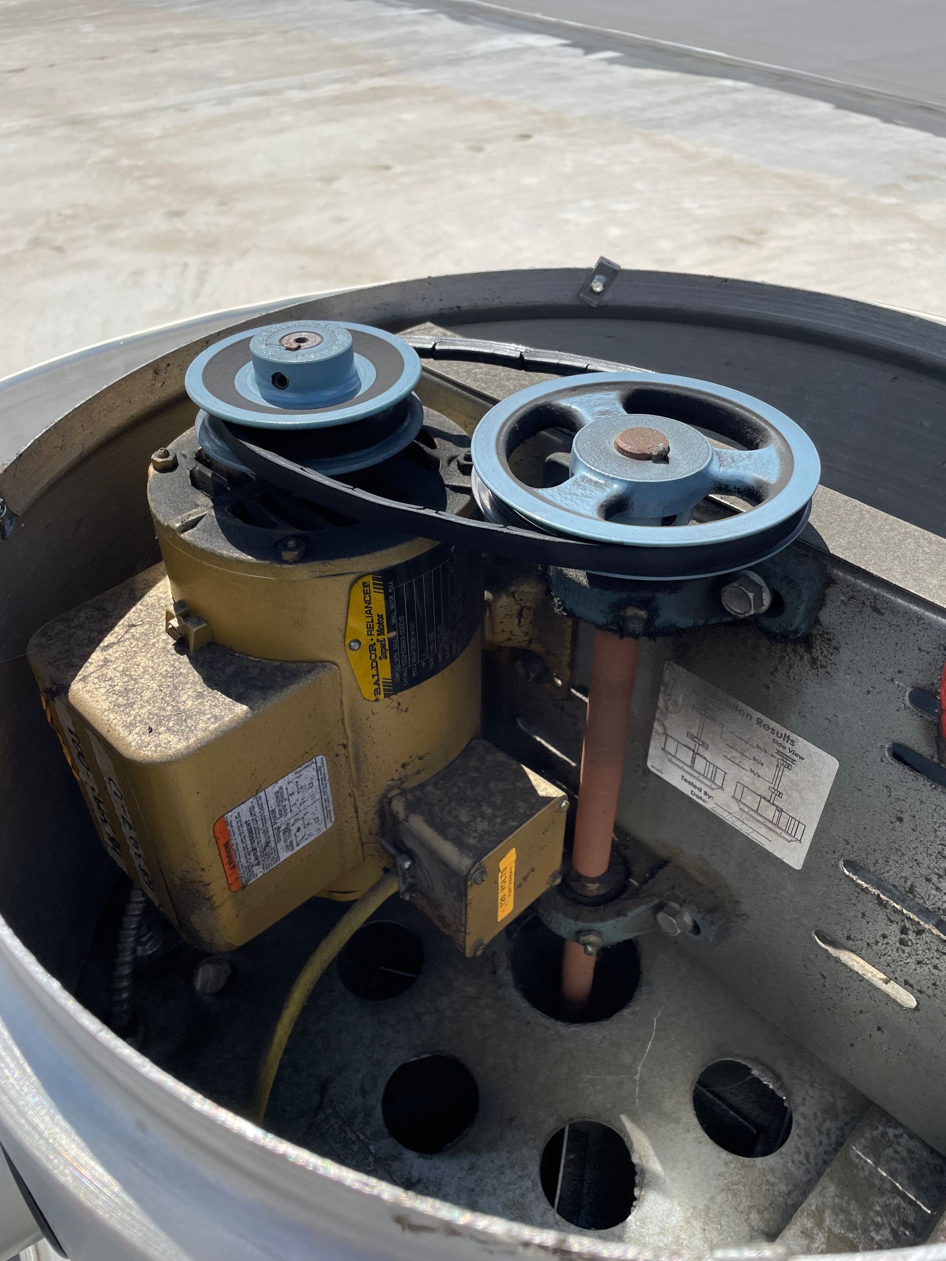 Motor and pulleys driving a fan inside a metal housing. Blue pulleys, yellow motor.