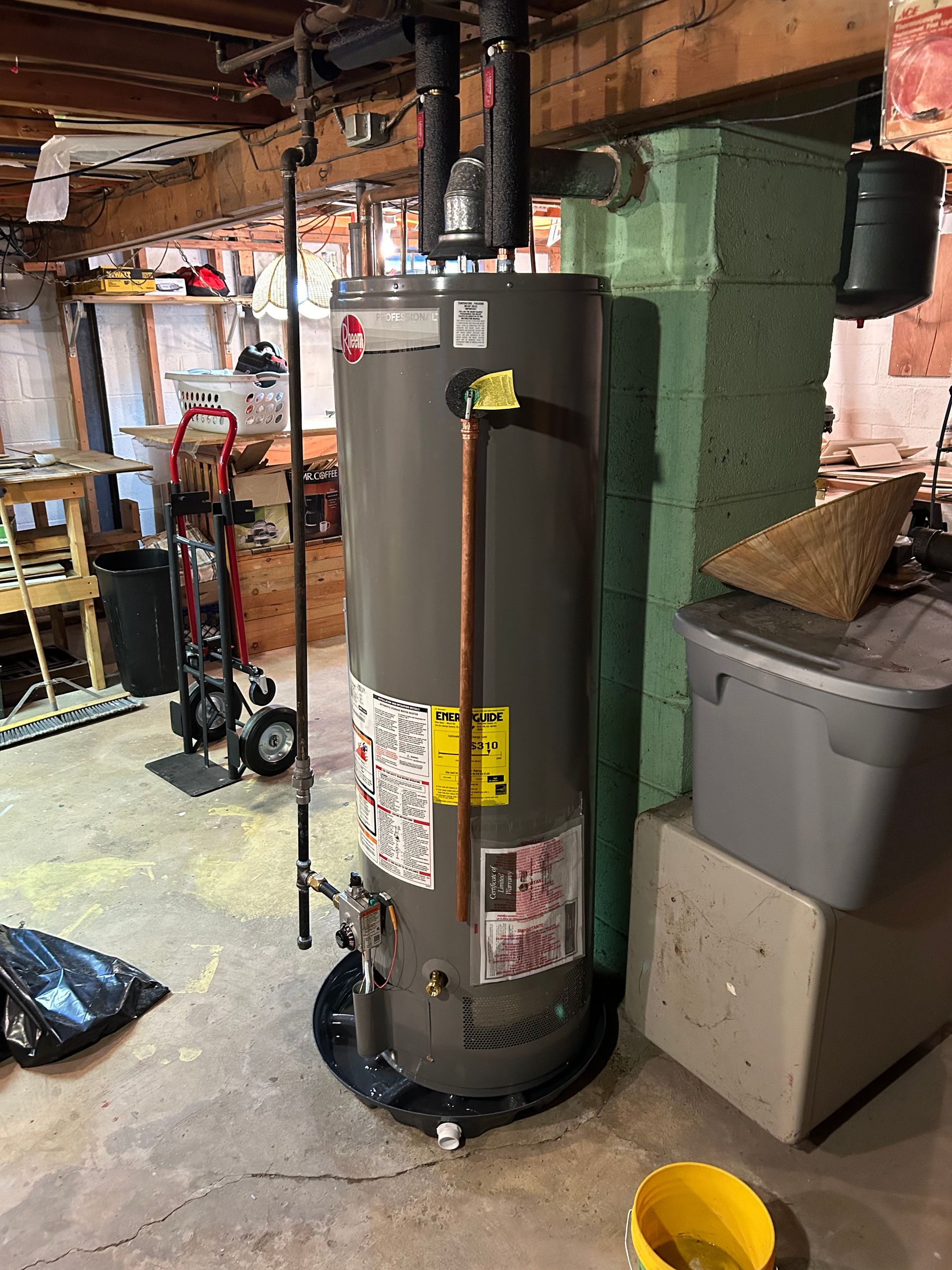 Water heater in a basement next to a support beam.
