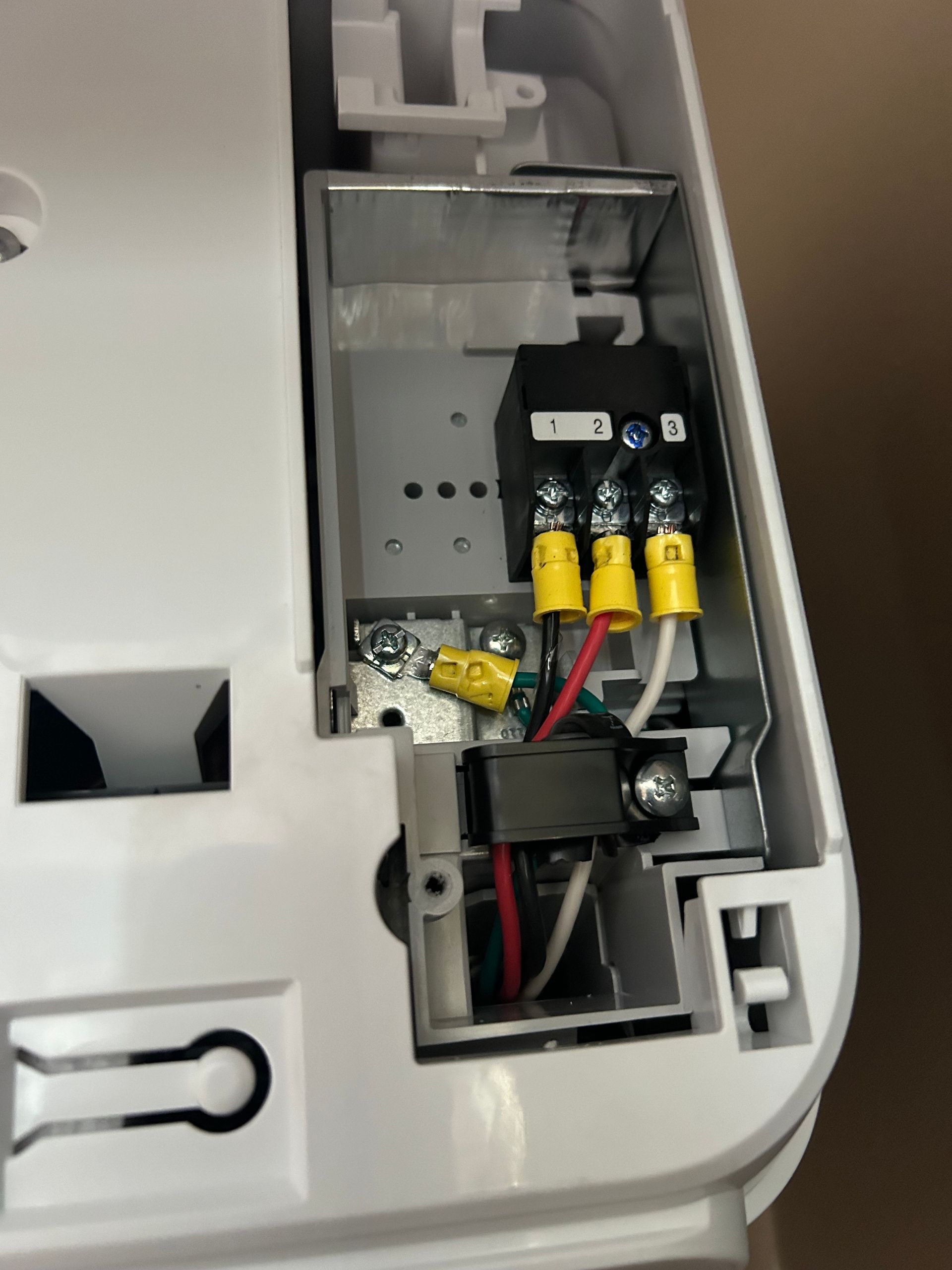 White appliance interior with electrical wiring; black, yellow, red, and white wires connected to terminals.