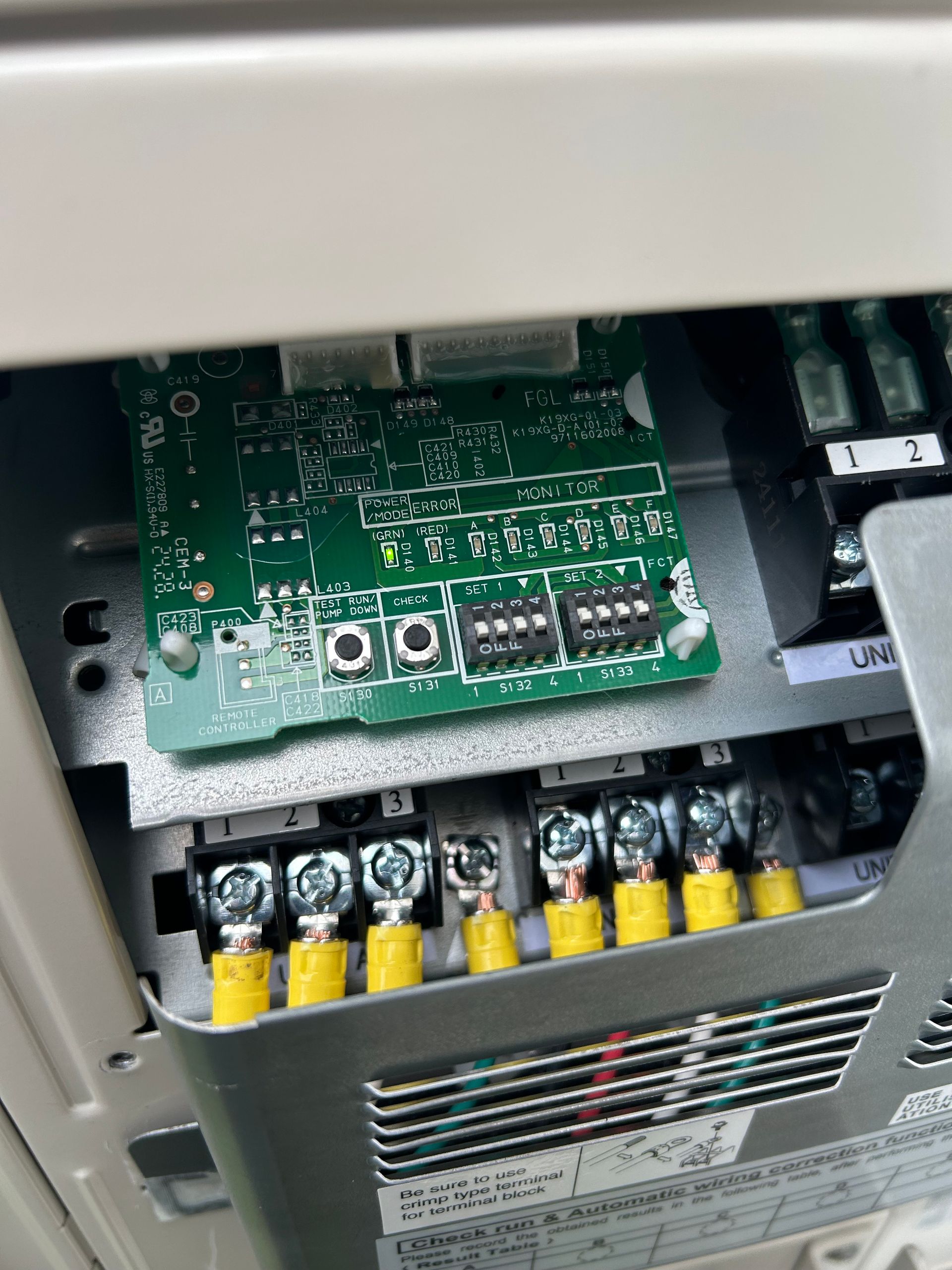 Close-up of an electronic circuit board with terminals and connecting wires in a metal housing.