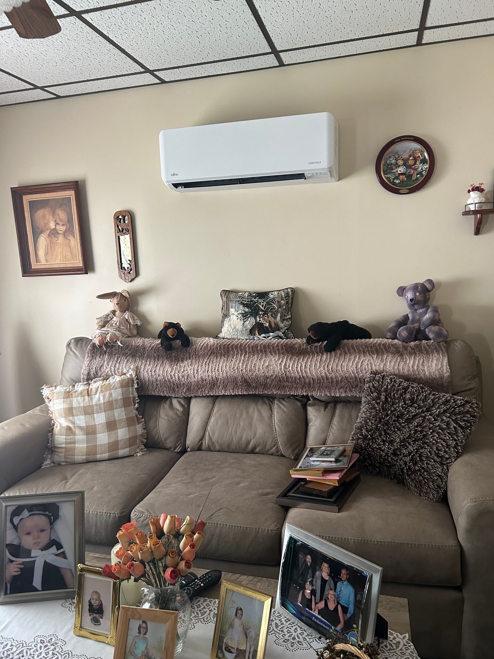Living room with couch, air conditioner, pictures, and decorations.