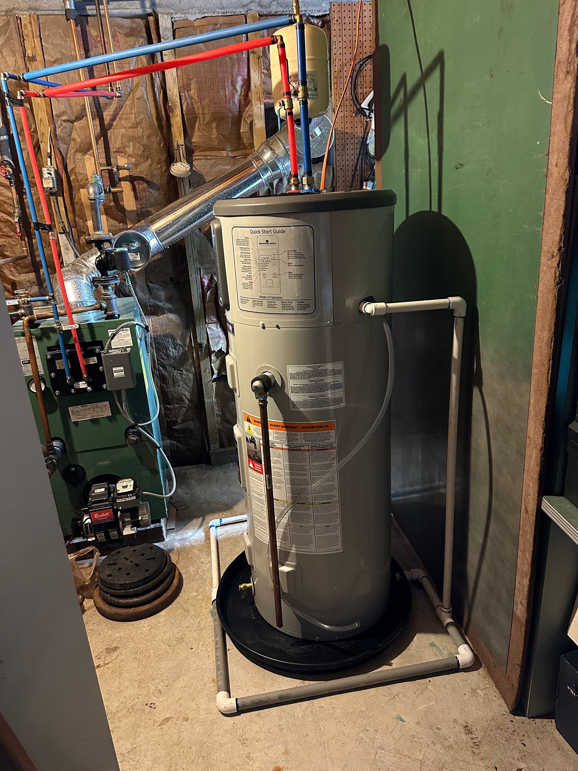 Water heater in a basement, surrounded by pipes.