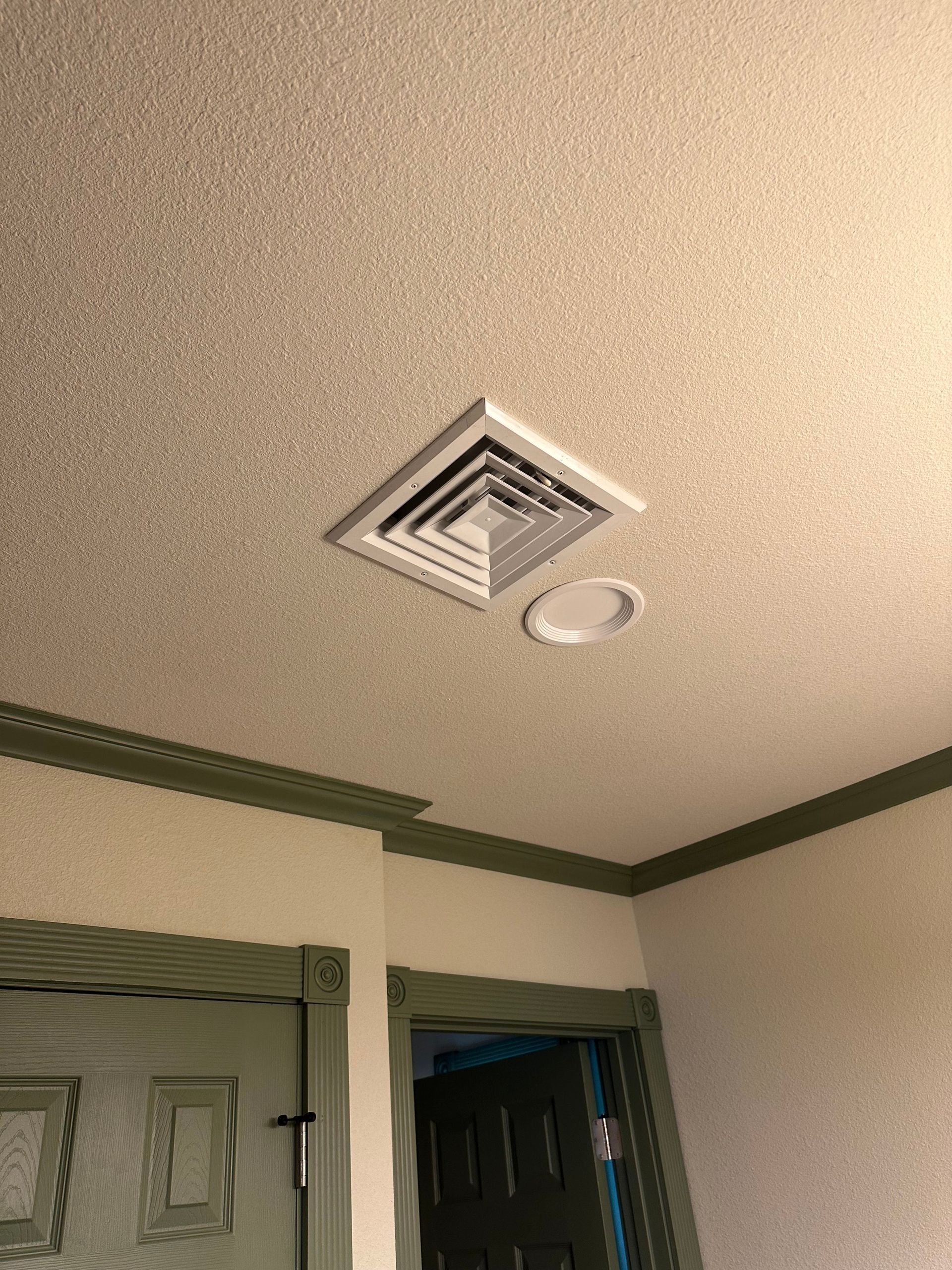 Ceiling with air vent, recessed light, and textured surface; green trim and doors in the room.