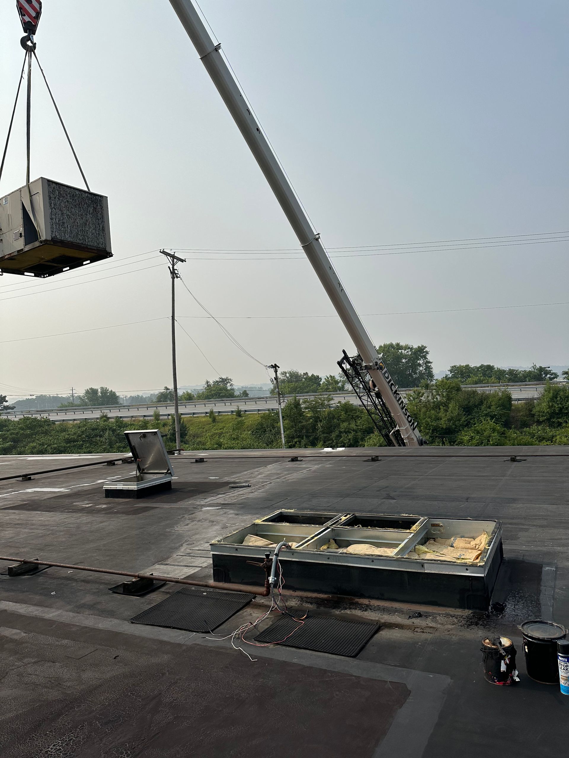 A crane lifts a large square object onto a flat roof.