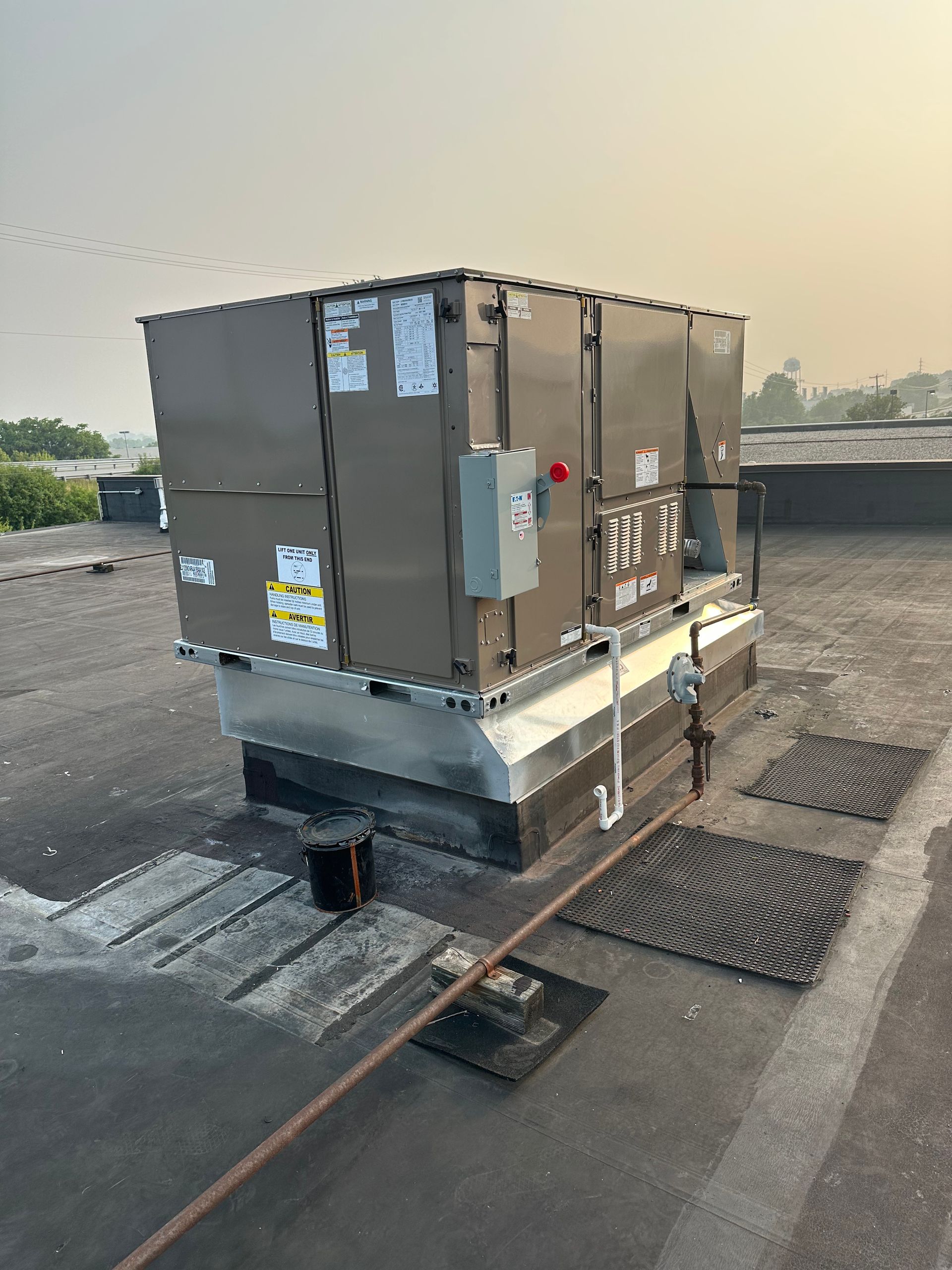 Rooftop HVAC unit; brown, metal; on a flat roof with gray surface, electrical box on side.