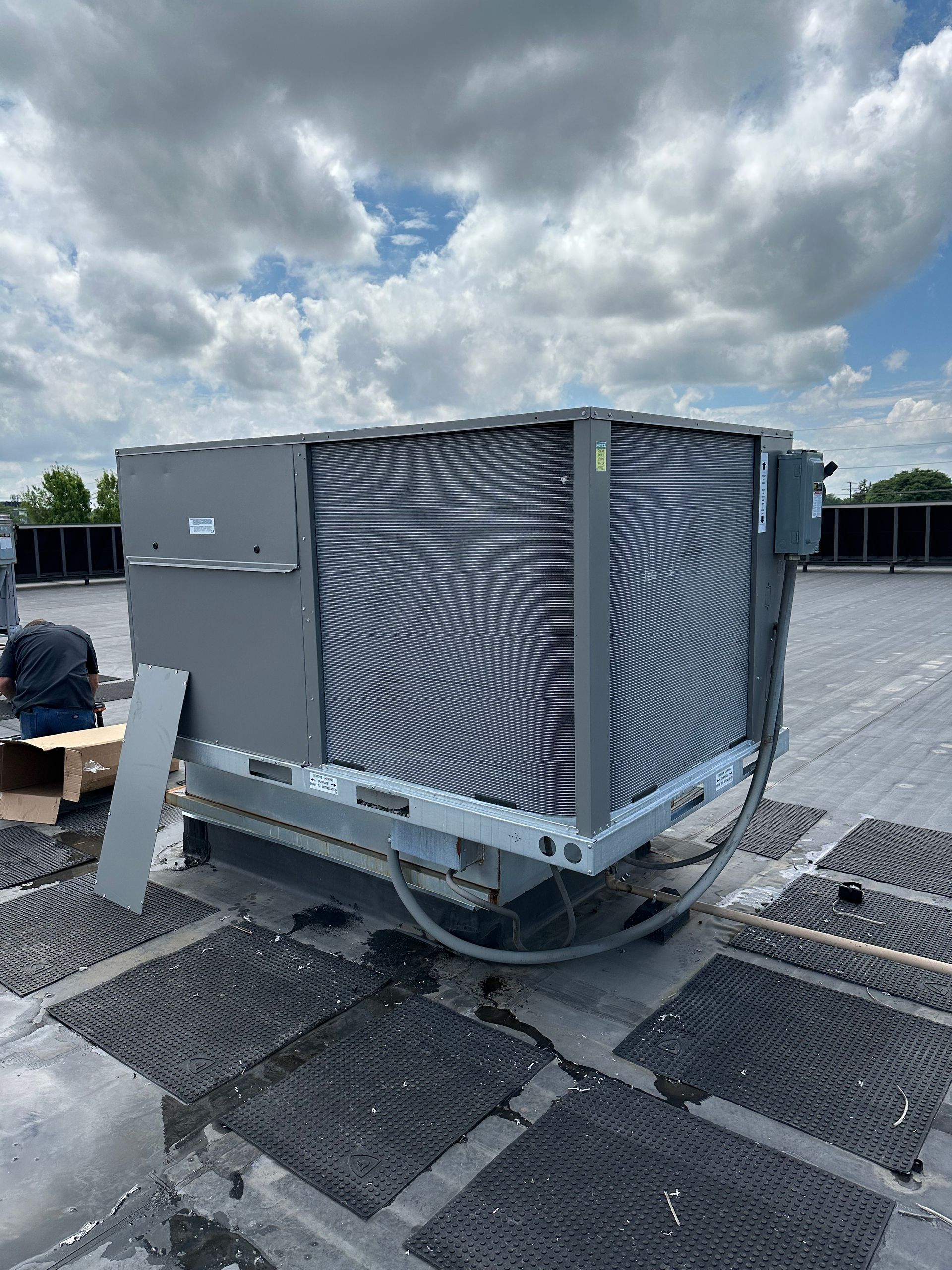 Large gray HVAC unit on a flat rooftop under a cloudy sky.