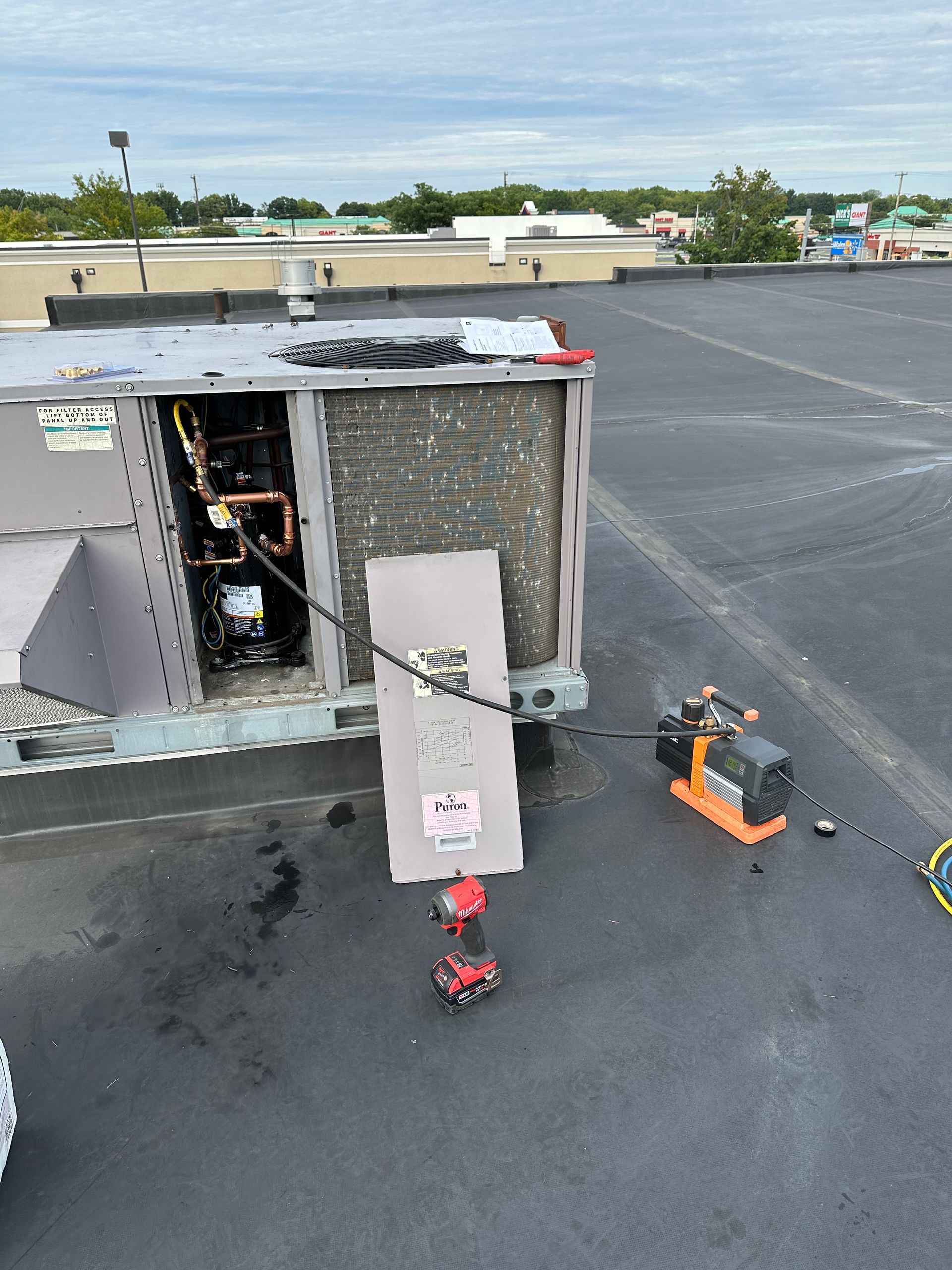 HVAC unit on a rooftop; a worker is making repairs.