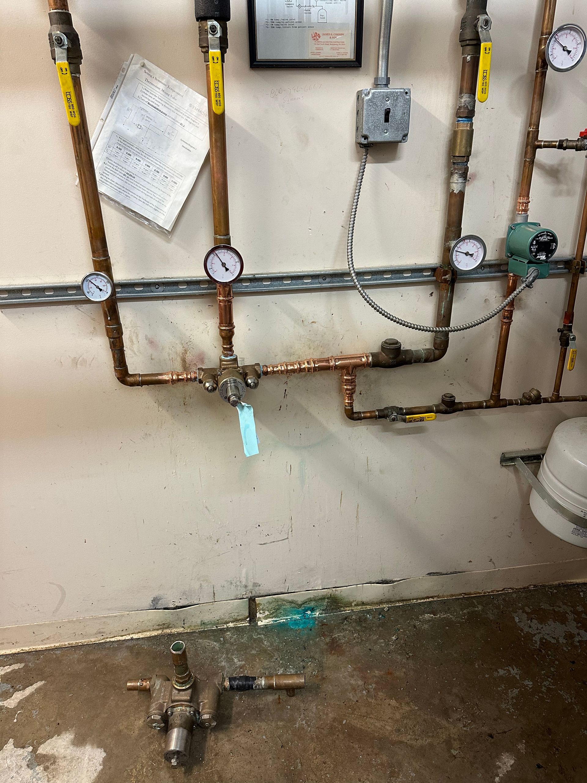 Copper pipes and gauges on a wall; an industrial setting.