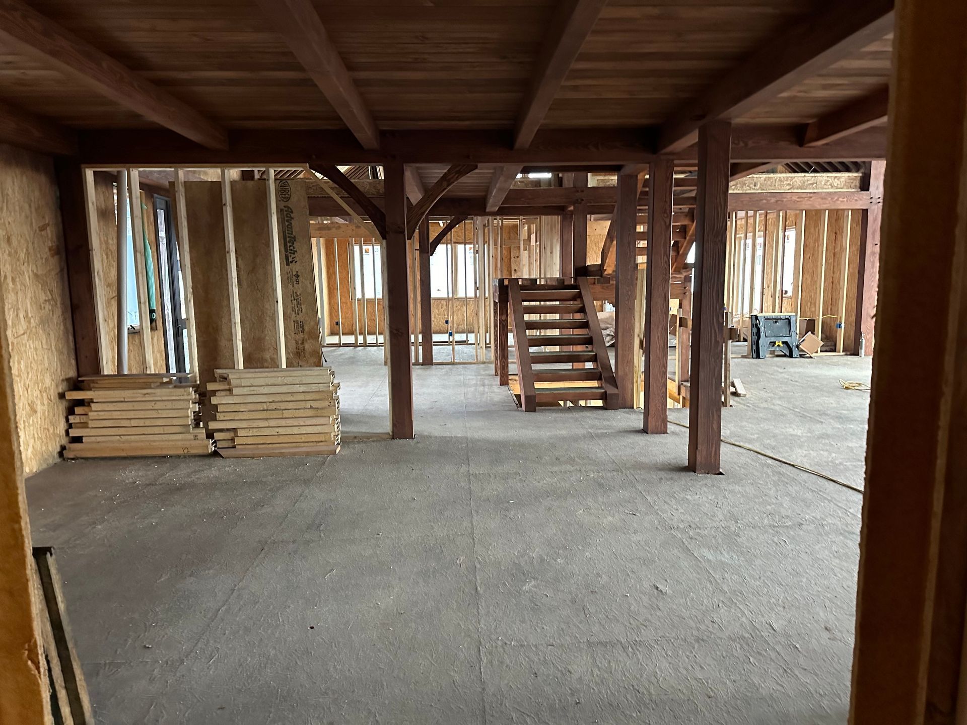 Interior of a building under construction with wood framing, stairs, and exposed beams.