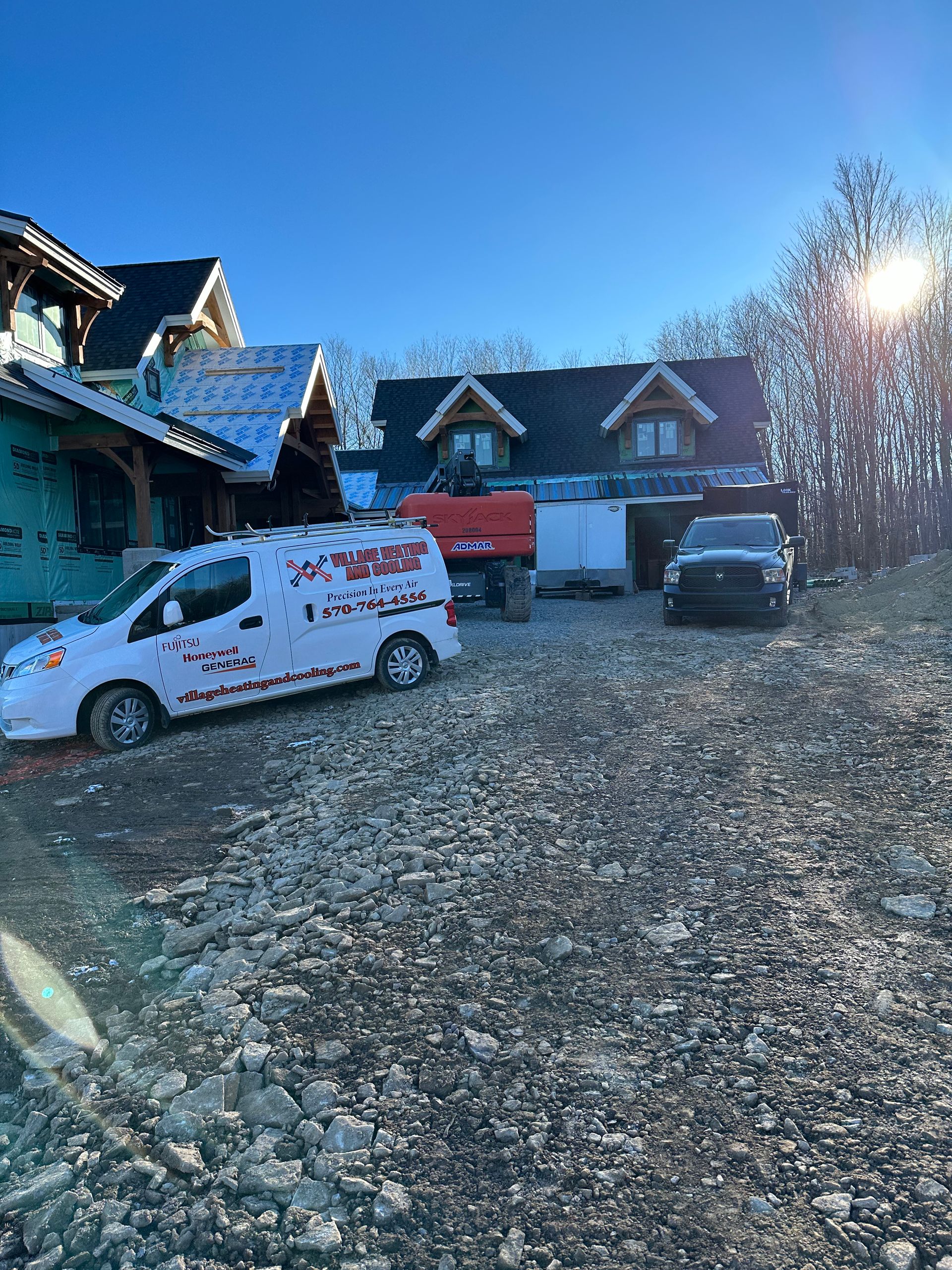 Construction site with vehicles, an excavator, and a partially built house under a sunny sky.