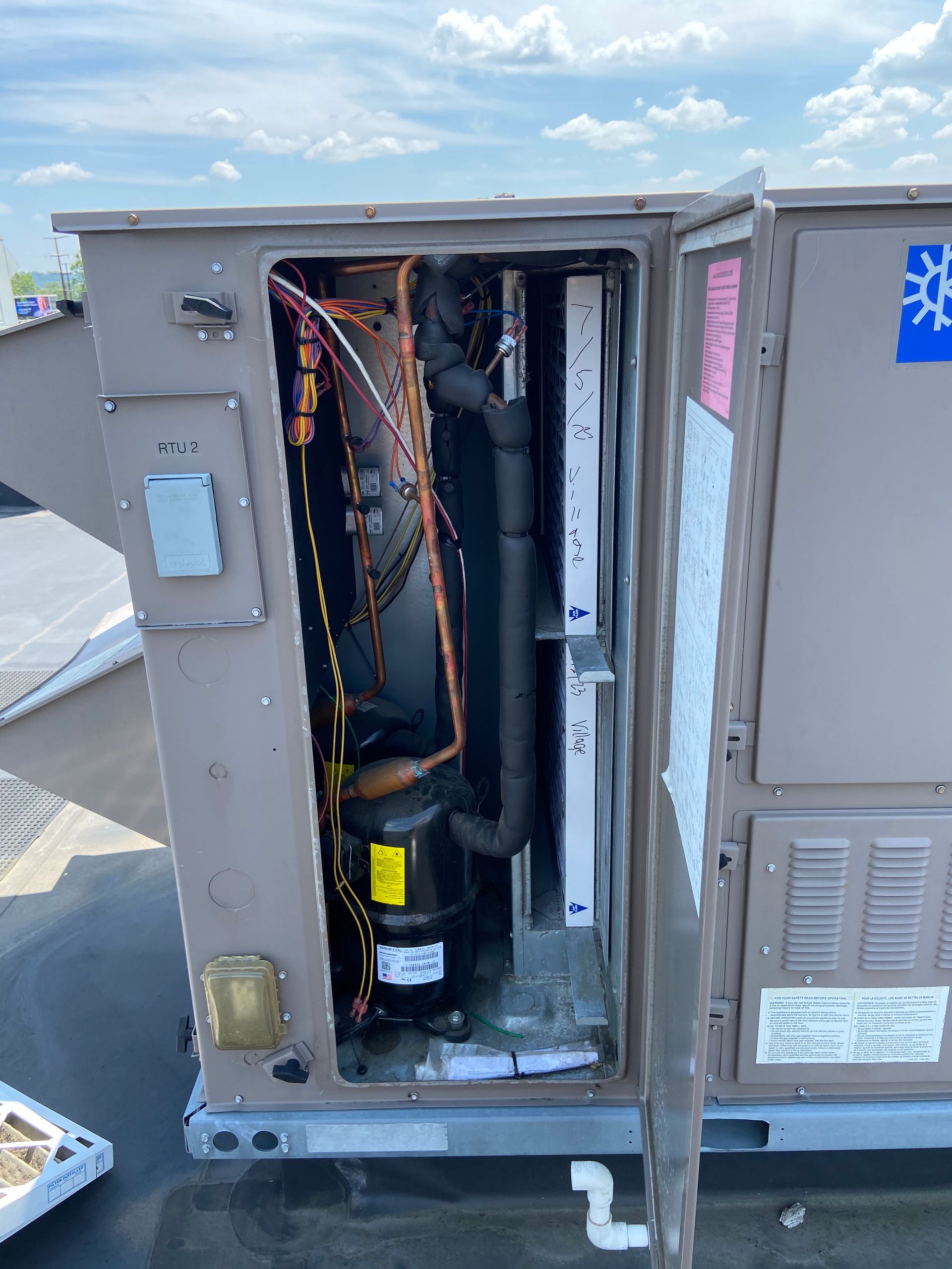 An open rooftop HVAC unit showing internal components like a compressor and coils.