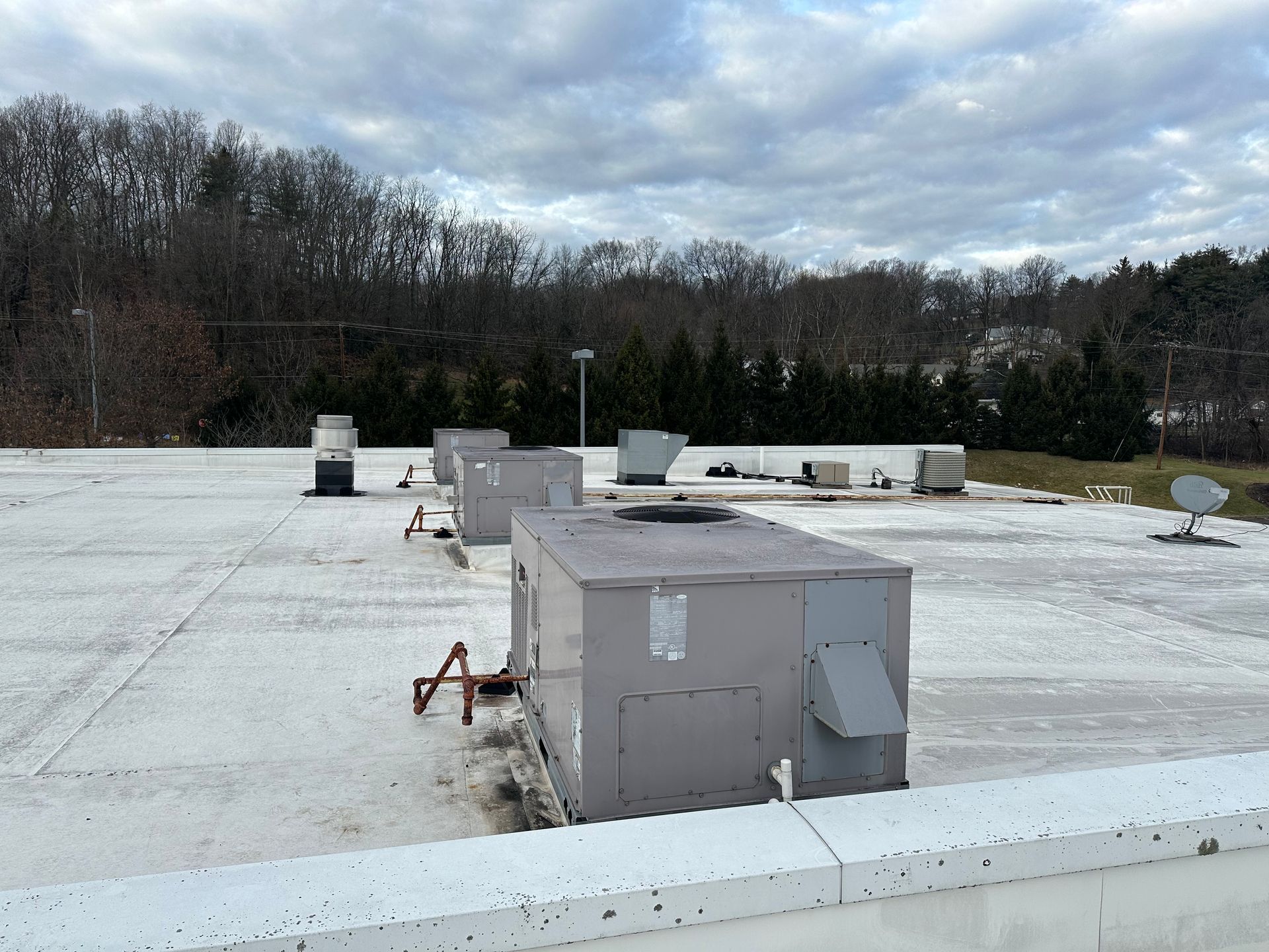 A commercial rooftop with HVAC units and a cloudy sky background.