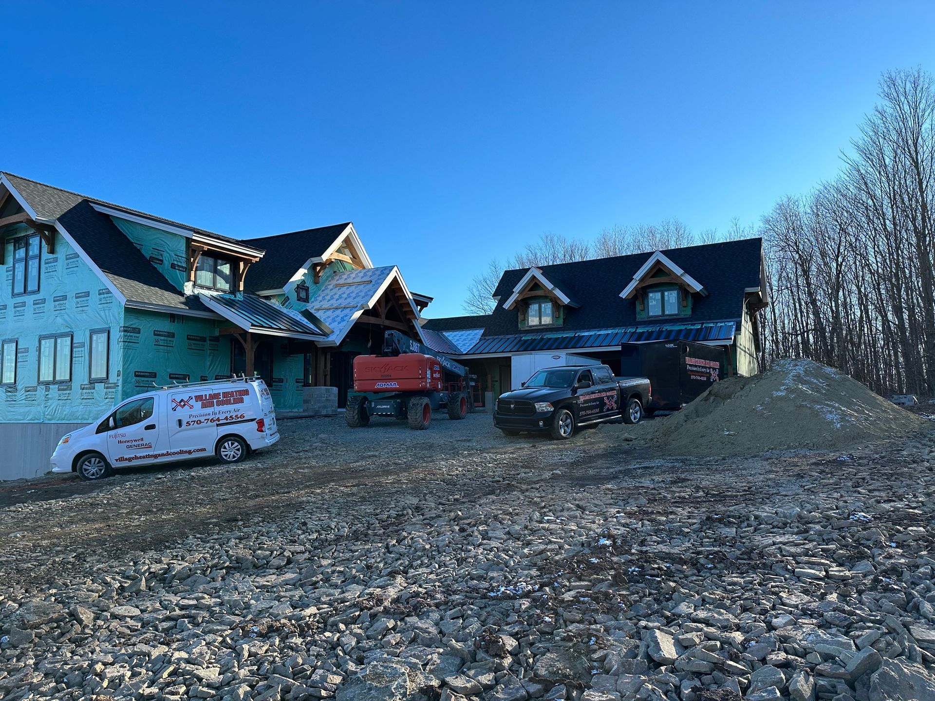 Construction site with two houses, vehicles, and a blue sky.
